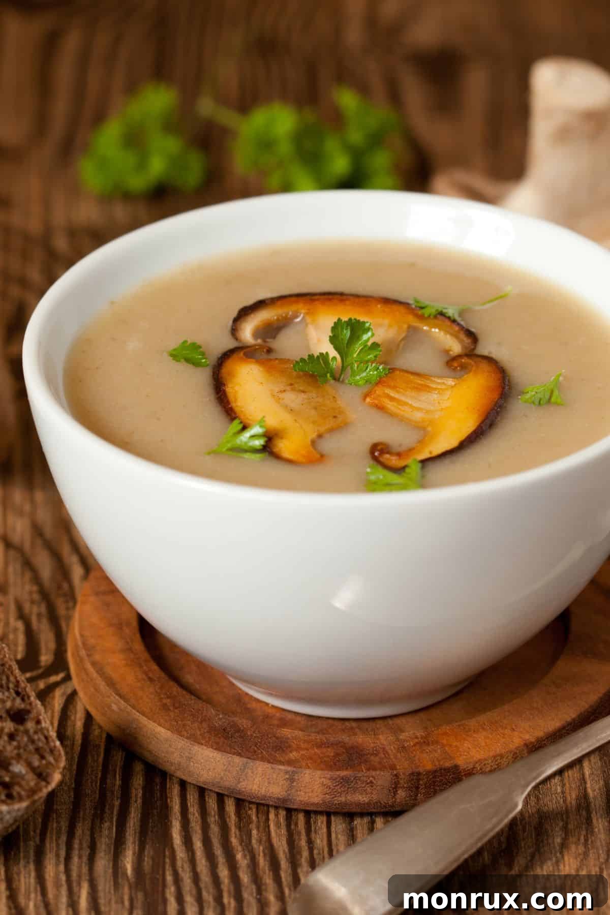 A bowl of dark, rich mushroom broth garnished with fresh mushrooms and herbs.