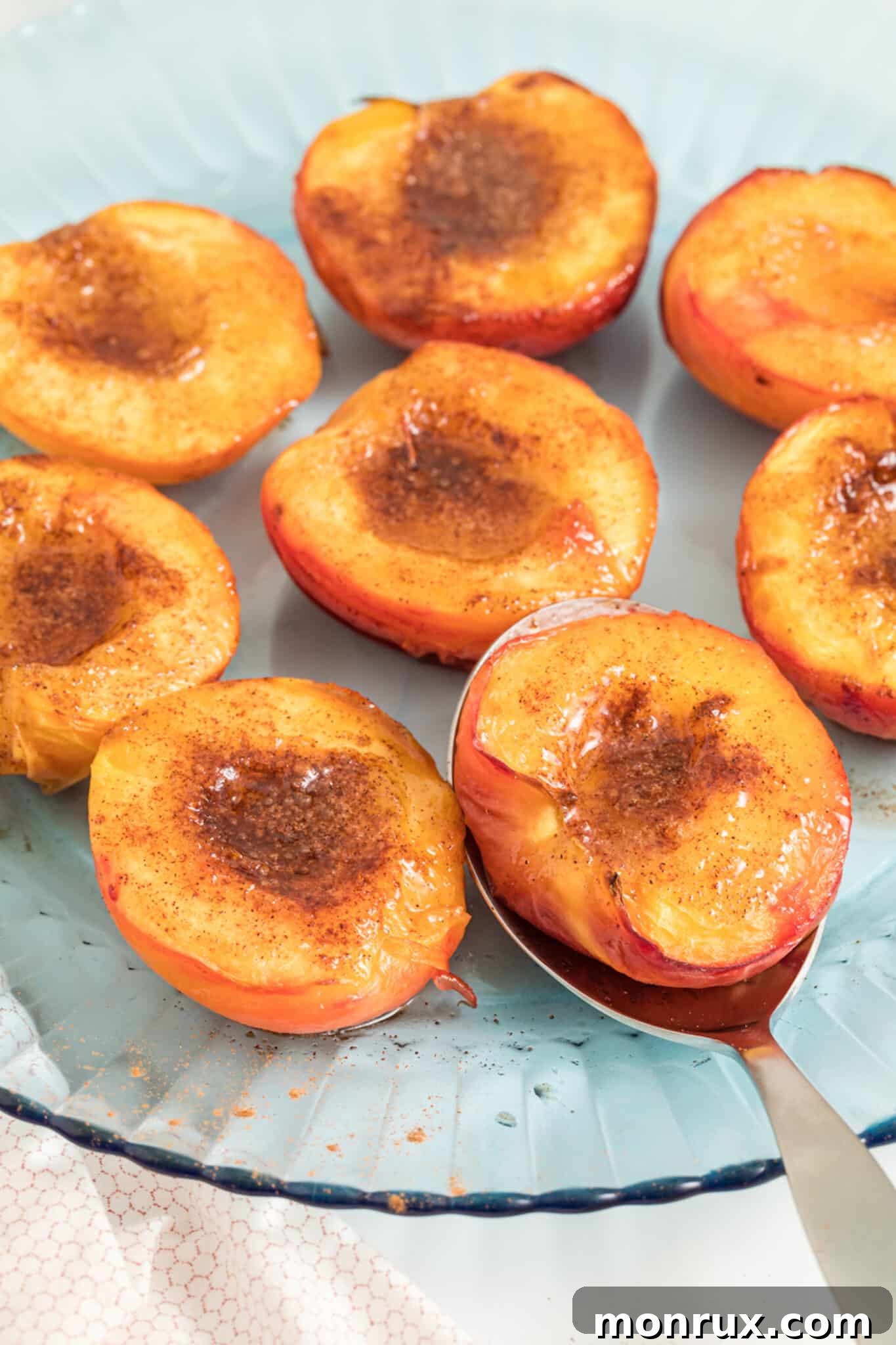 Perfectly caramelized air fryer peach halves, glistening and golden brown, arranged artfully on a serving platter, ready to be enjoyed as a healthy and delicious dessert.