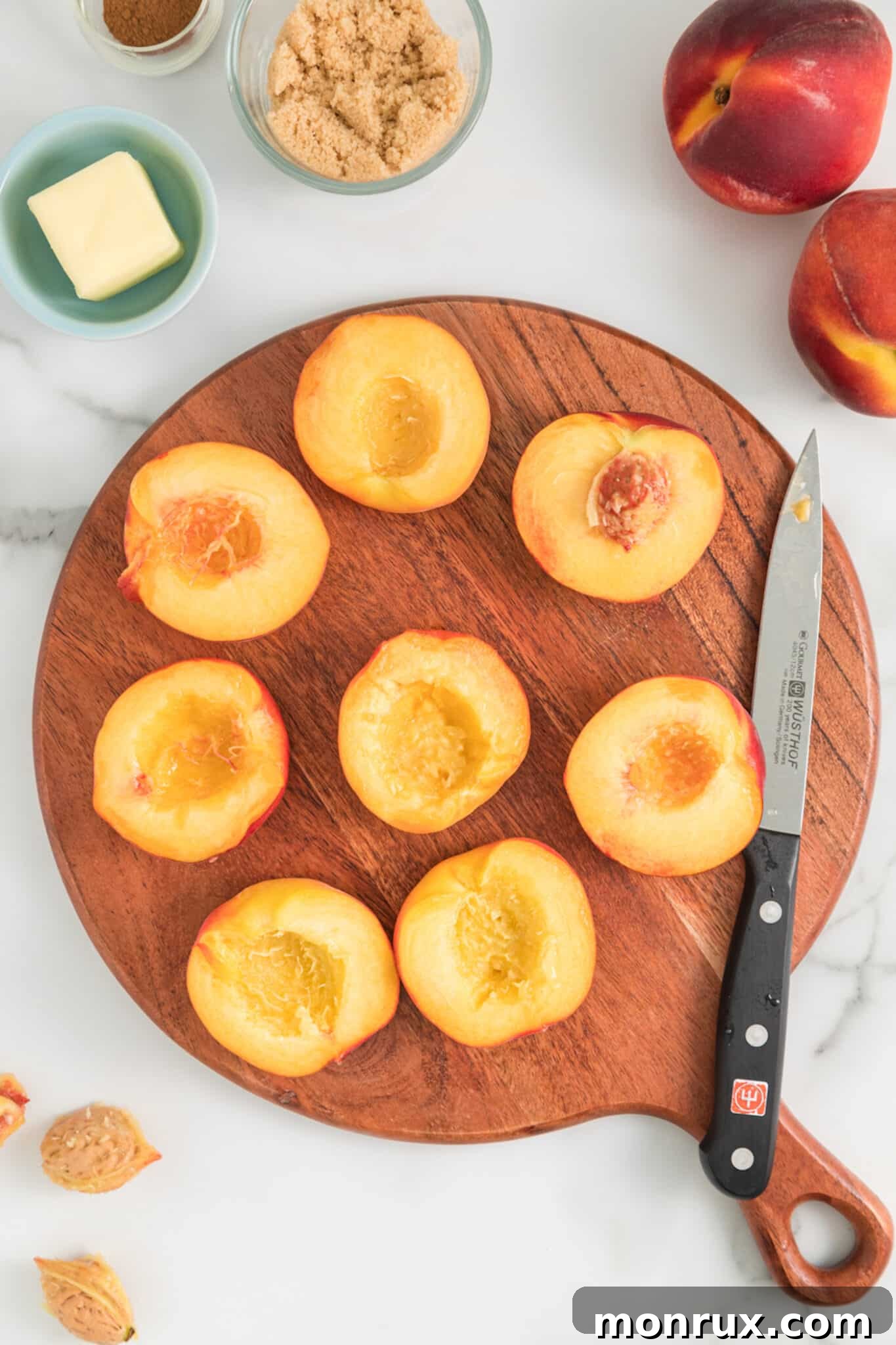 The first step in making air fried peaches: a chef's hand carefully removing the pit from a halved ripe peach using a sharp knife.