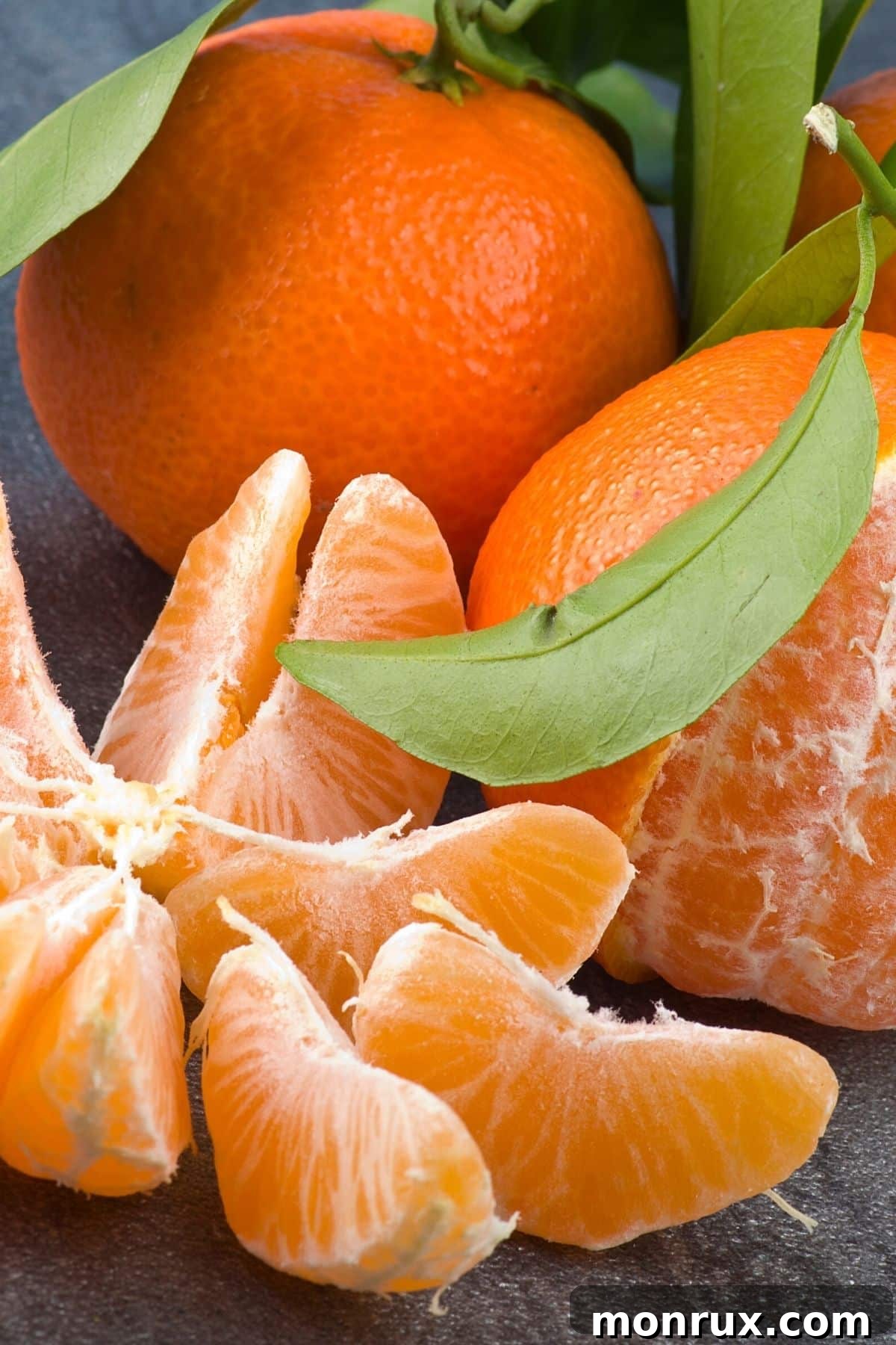 Vibrant tangerines, some peeled and others whole, resting on a rustic wooden table, showcasing their bright orange color and inviting texture.