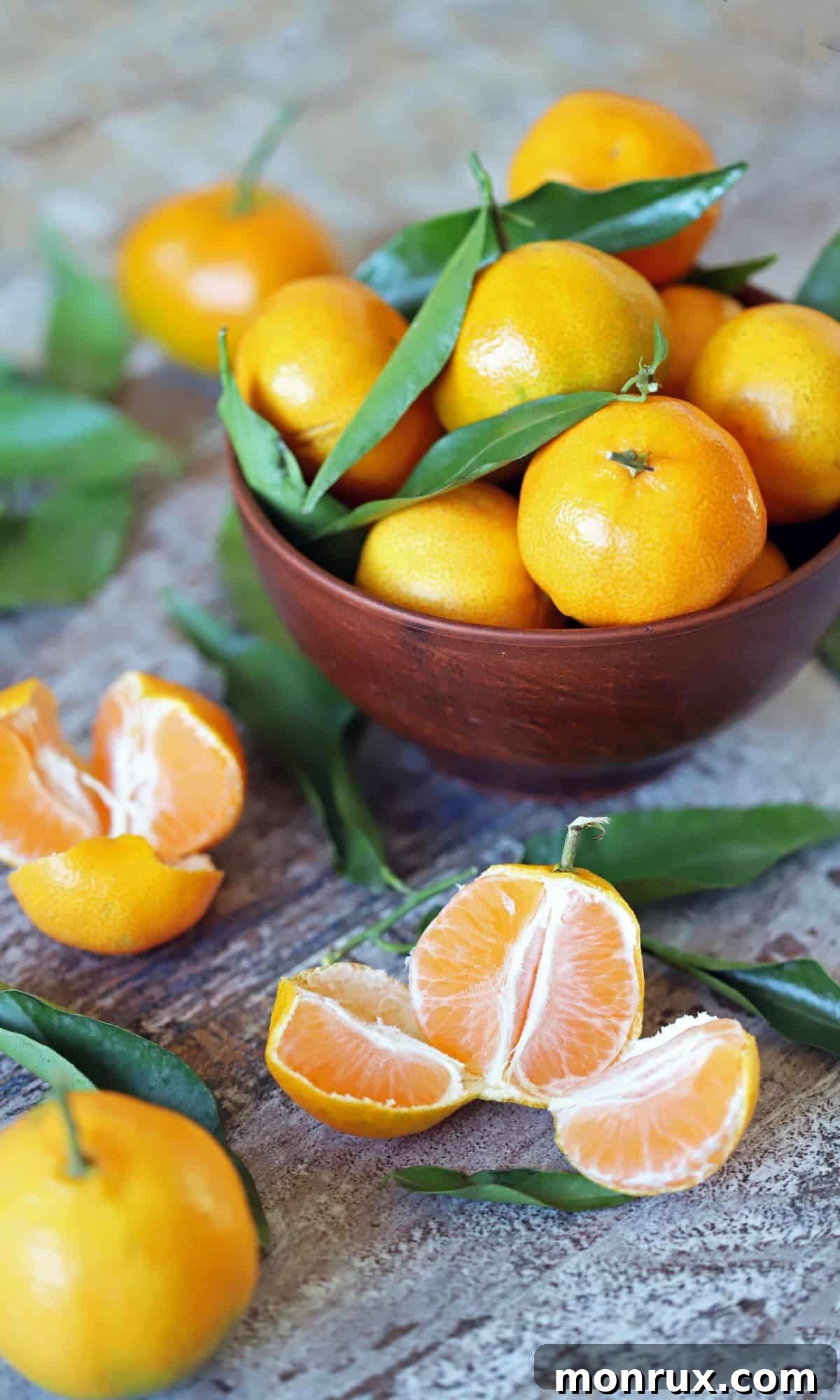 A wooden bowl filled with whole tangerines and several peeled tangerines scattered on a table, highlighting their easy-to-peel skin and juicy segments.