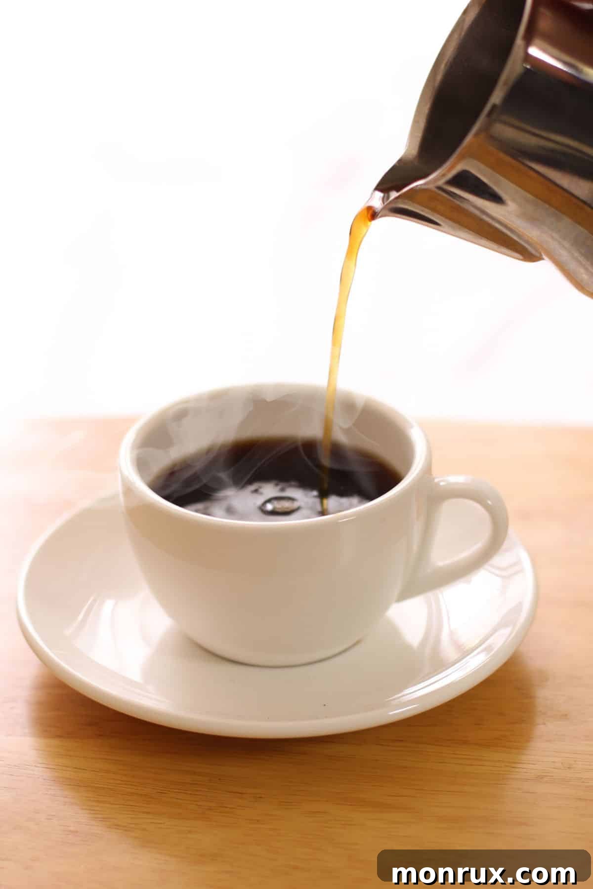 someone pouring coffee into a white mug. A perfect, steamy cup of organic decaf coffee ready to be enjoyed.