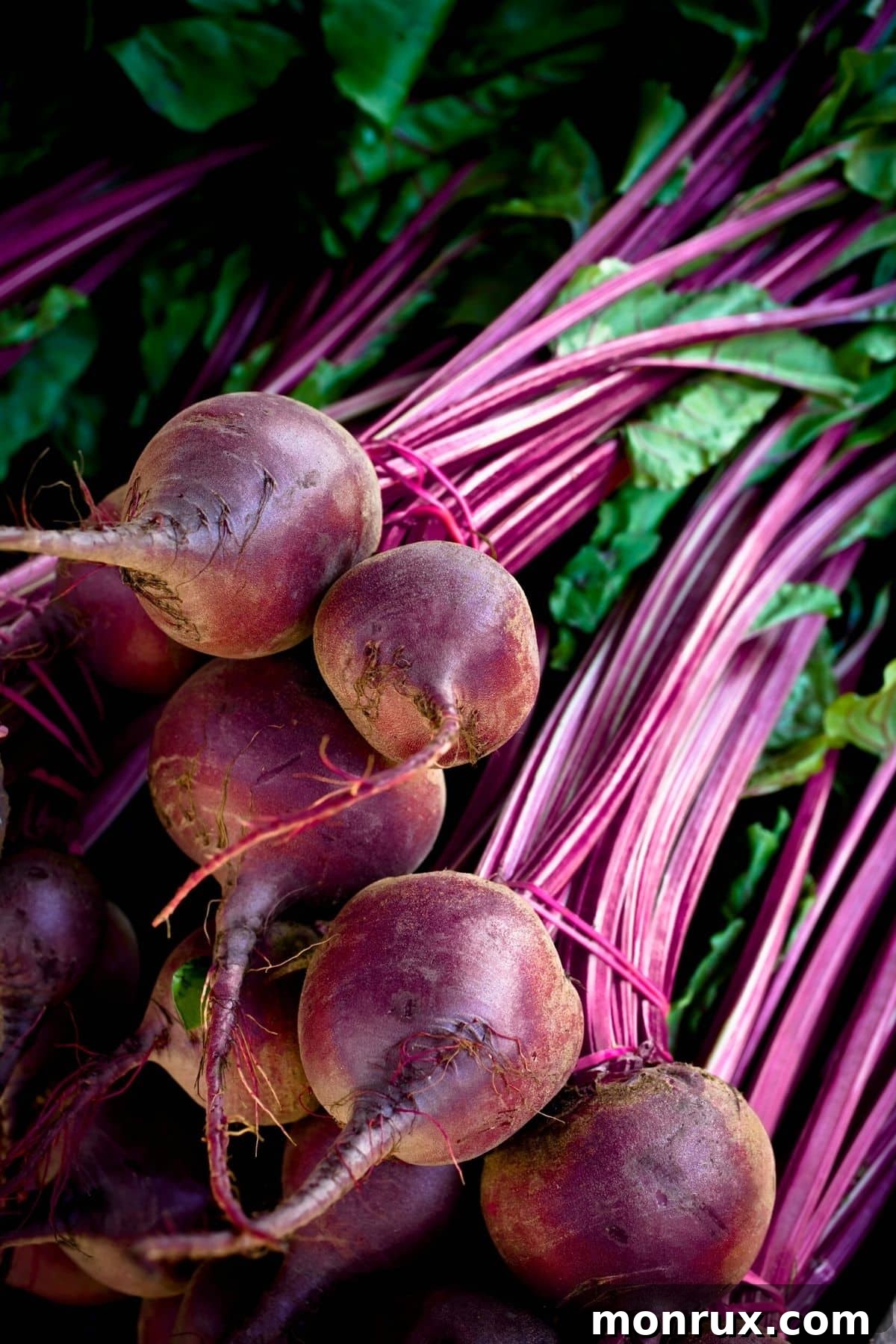 Fresh, deep red beets on a wooden table, indicating their earthy goodness.