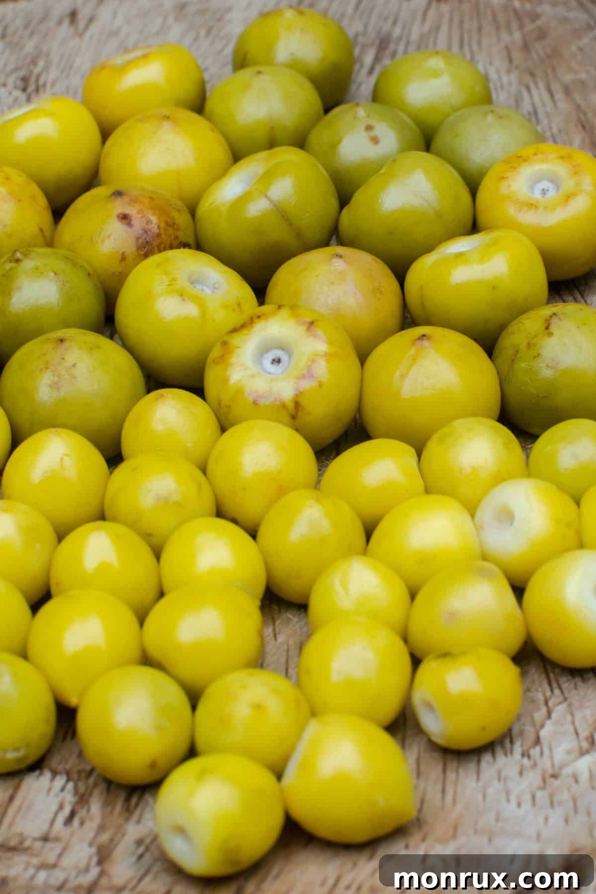 A cluster of small, yellow-orange Nance fruits with green leaves in the background.