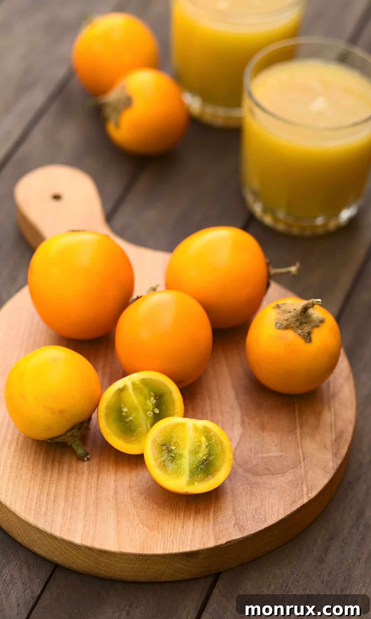 Sliced and whole fuzzy Naranjilla fruits on a wood slice, revealing their vibrant green interior.