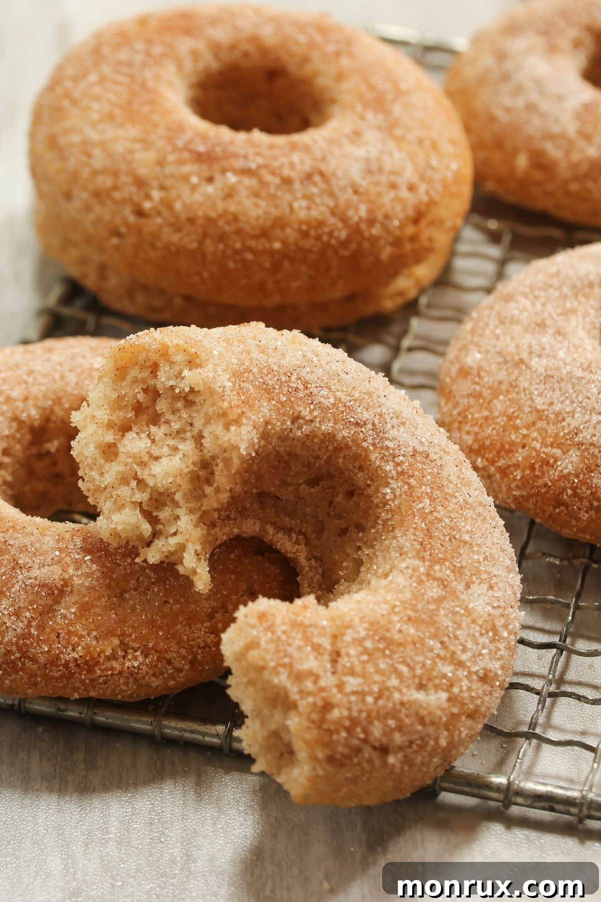 Apple Cider doughnuts with cinnamon sugar on cooling rack.