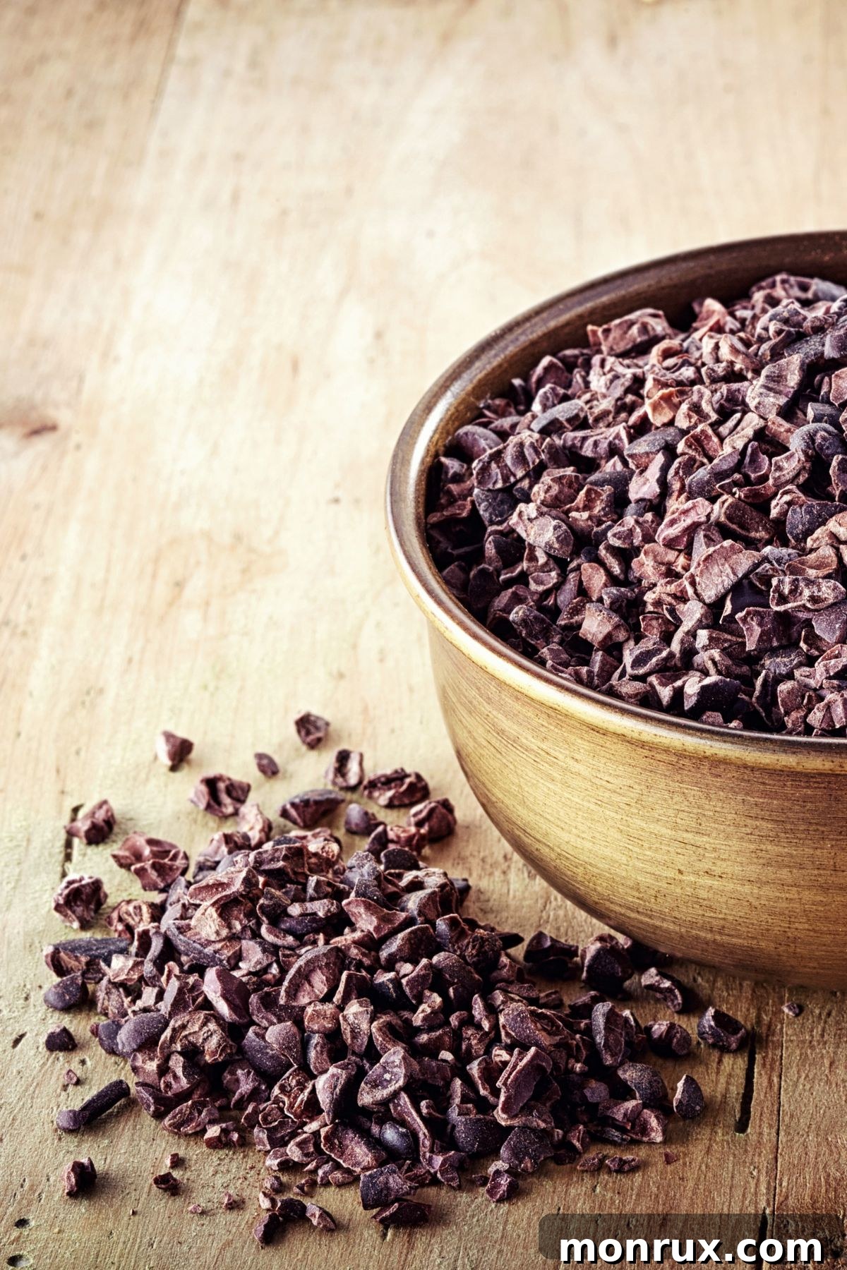 A small bowl filled with dark, crunchy cacao nibs, ideal for grinding into a powder for baking or as a healthy snack.