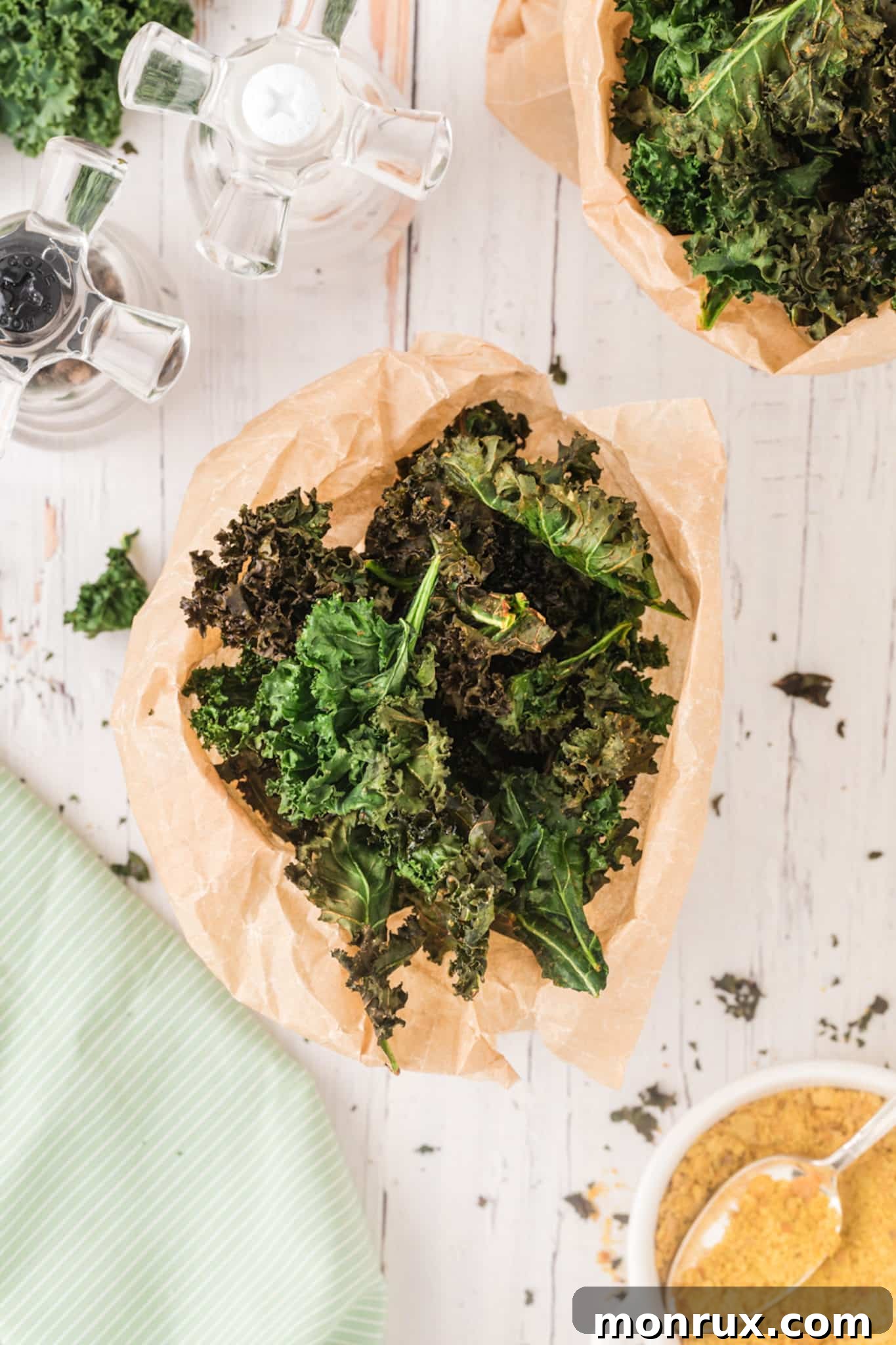 A generous serving of vibrant green kale chips seasoned and ready to eat in a bowl.