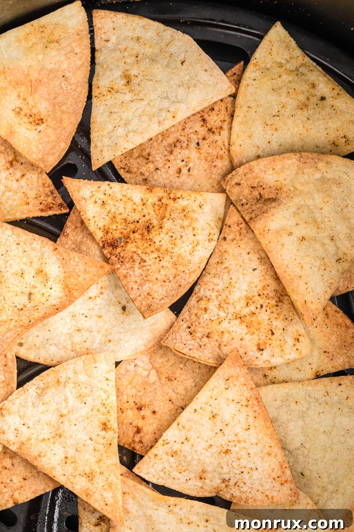Close-up of golden, crispy homemade corn tortilla chips arranged in an air fryer basket.