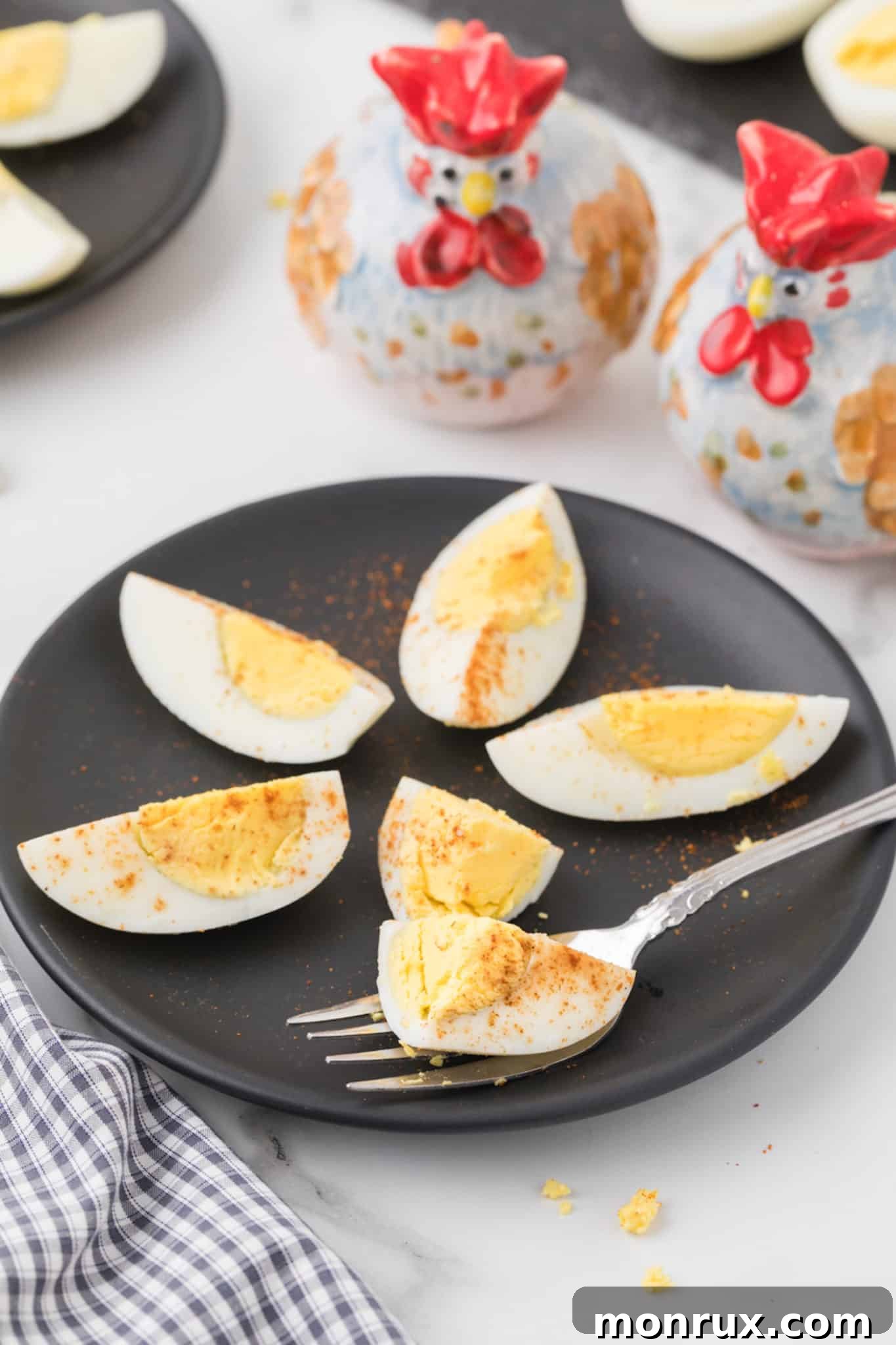 Several hard-boiled eggs, perfectly sliced in half, arranged neatly on a pristine white plate.