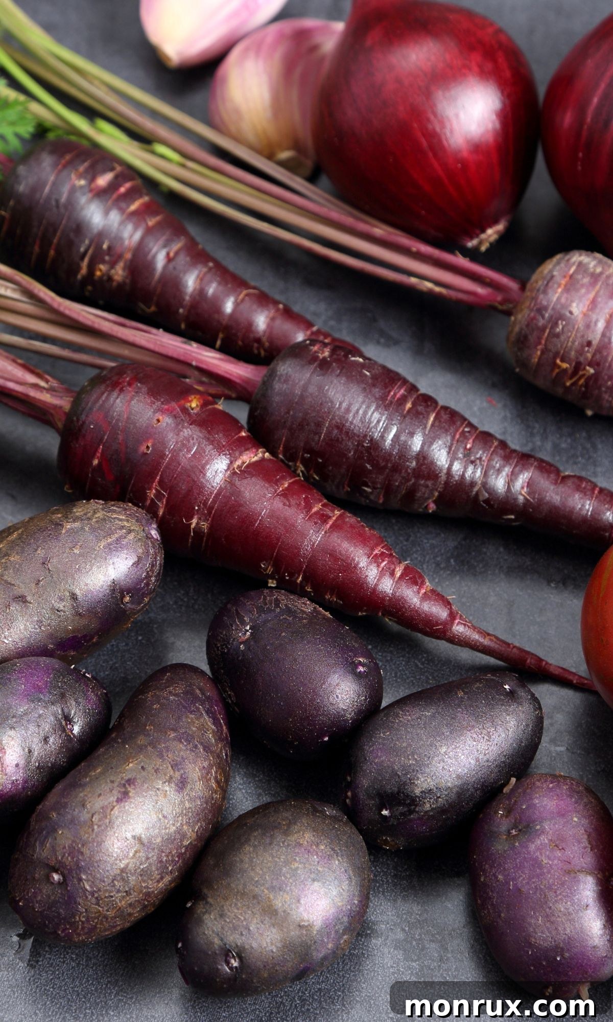 A vibrant harvest of blue carrots and potatoes artfully arranged on a wooden surface, showcasing their unique natural colors.