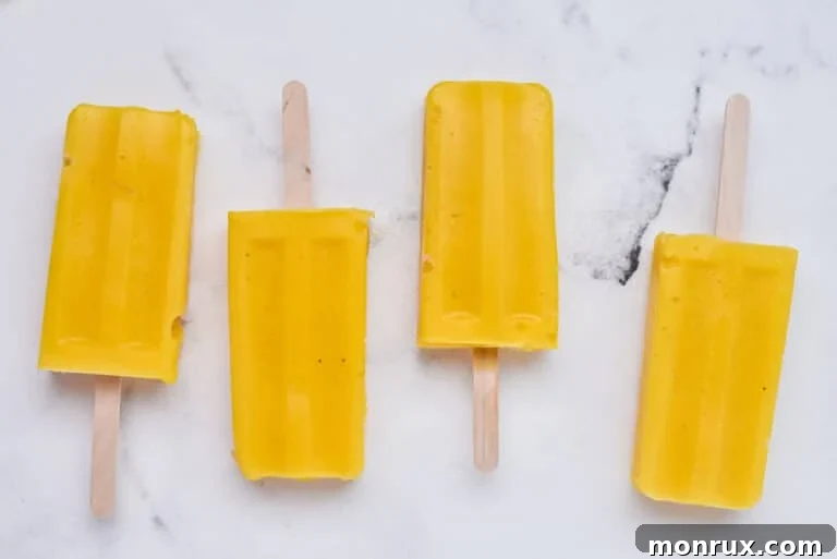 Frozen mango popsicles on a plate, ready to be served and enjoyed.