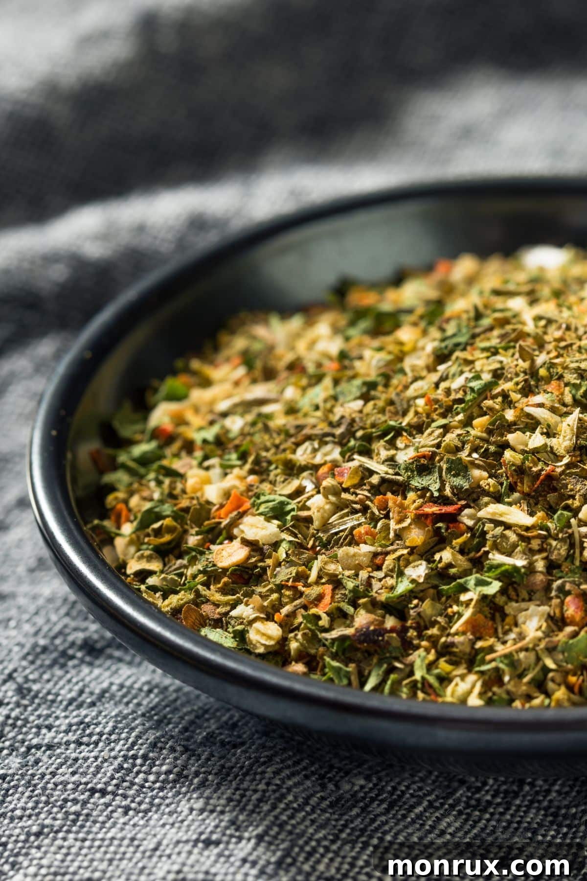 Bowl of Italian Seasoning on dish cloth, illustrating the common blend of herbs used in cooking.
