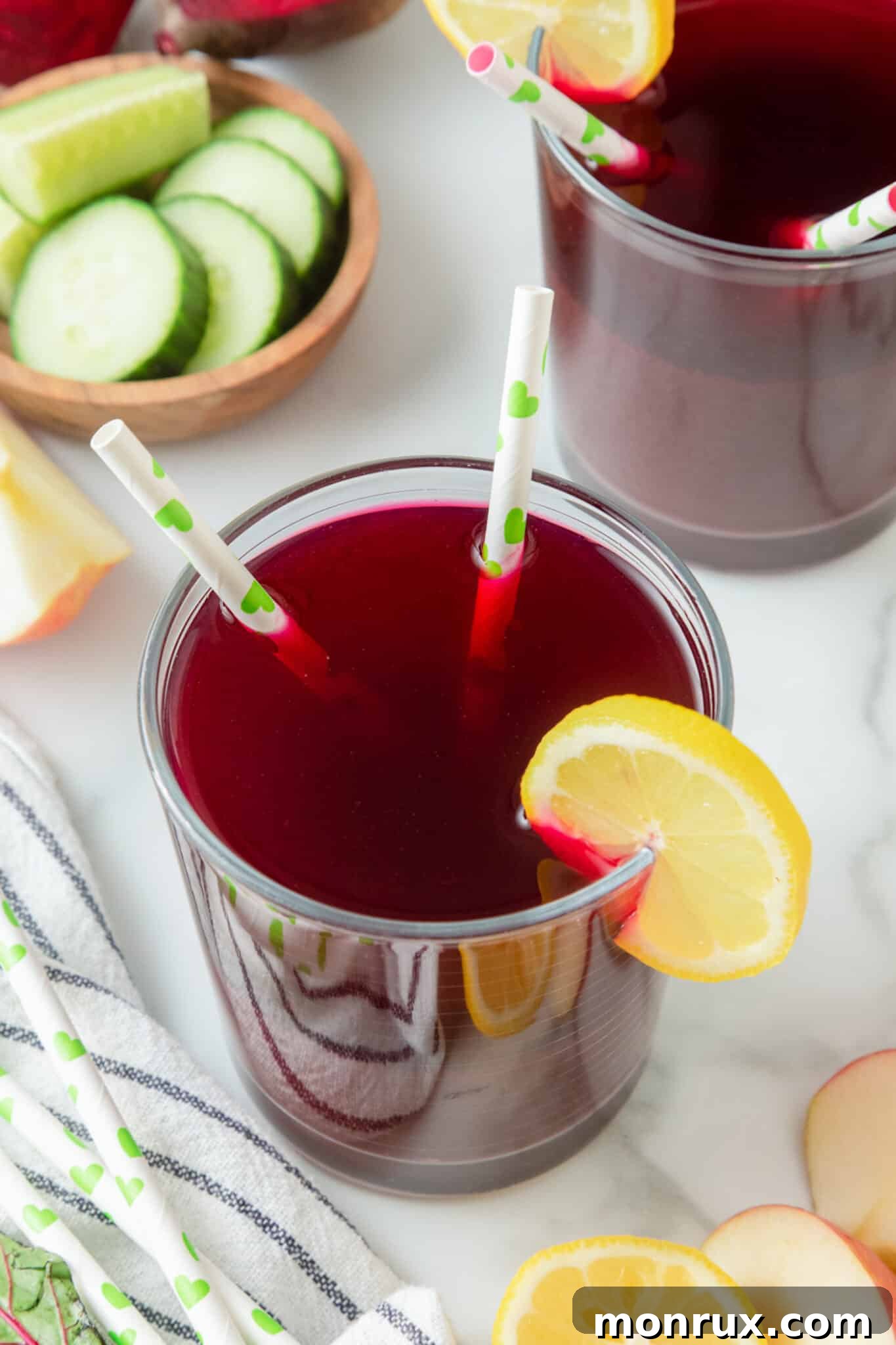 A vibrant glass of red liver cleanse juice with two straws and a fresh lemon slice, ready to be enjoyed.