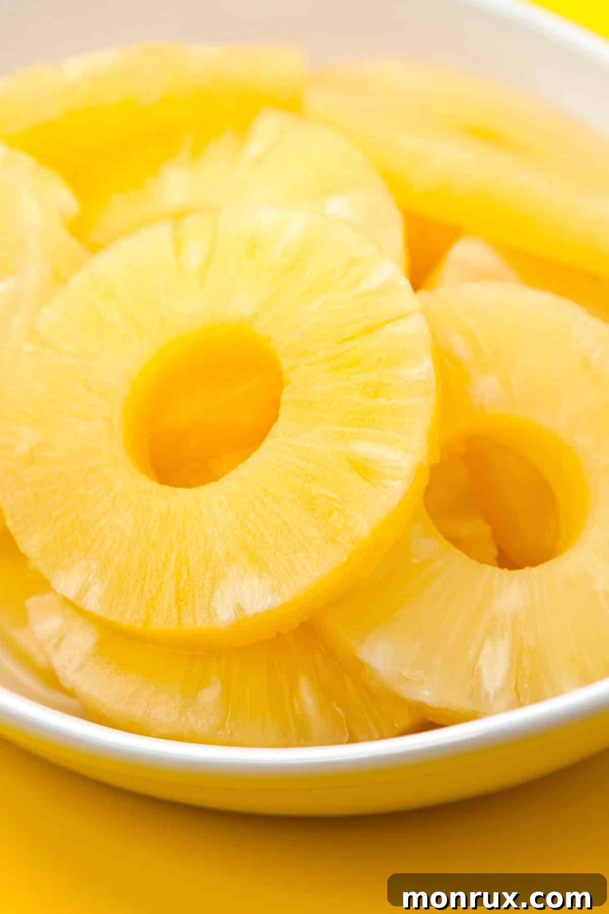 Canned pineapple rings in a white bowl, ready for draining and preparation.
