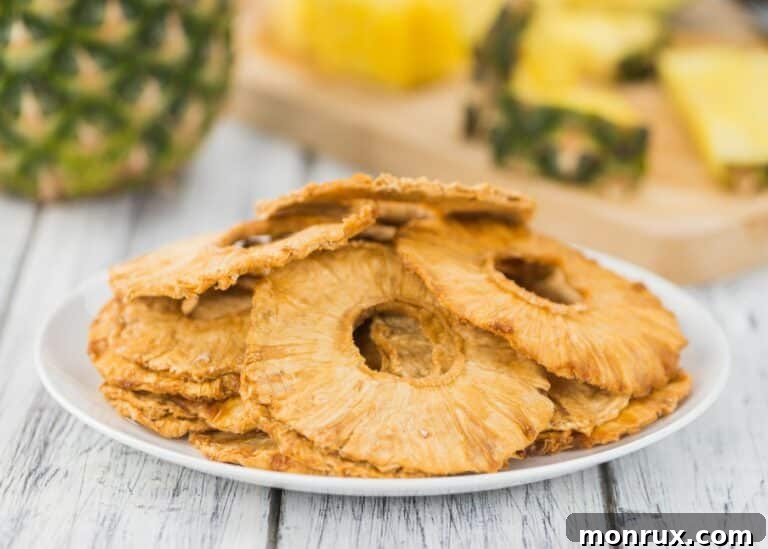 A pile of dehydrated pineapple slices on a white plate, golden and chewy.