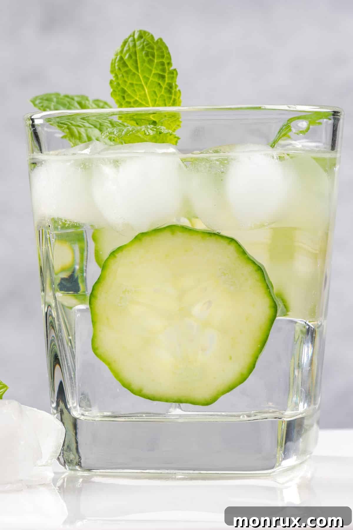 A refreshing glass of water garnished with fresh cucumber slices and infused with cucumber ice cubes.