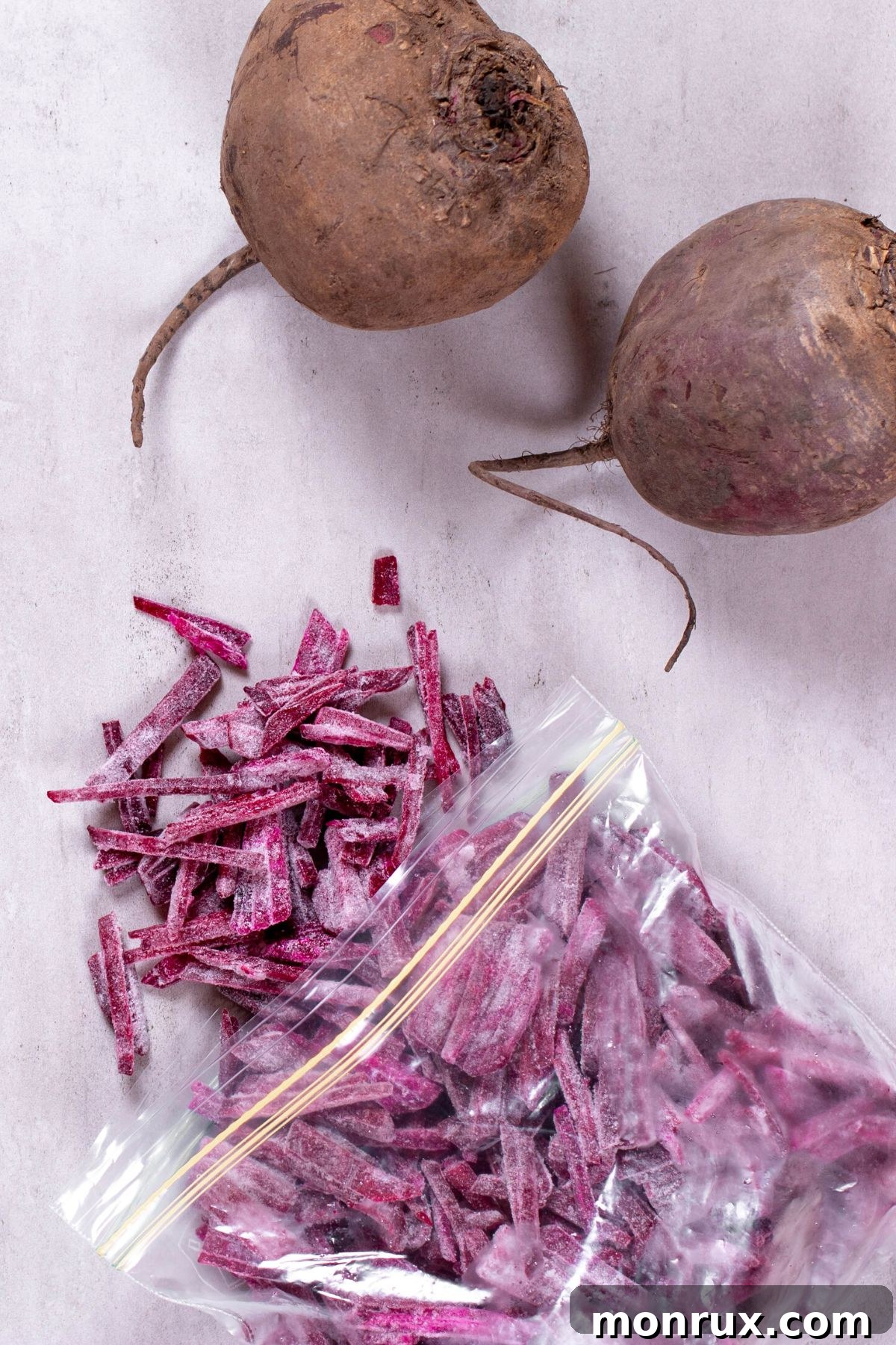 A baggie of frozen shredded beets next to two whole beets, showcasing the preservation method.