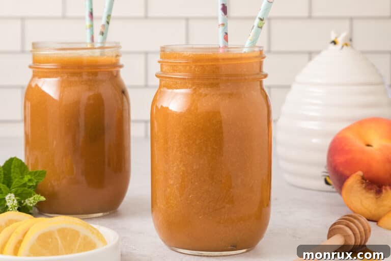 Two mason jars filled with fresh peach juice, garnished with peach slices and straws.