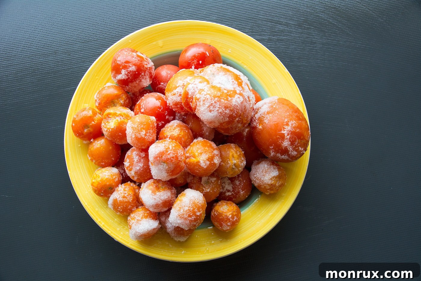 A plate filled with perfectly frozen cherry tomatoes, individual and ready for storage.