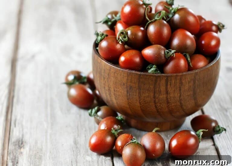 A wooden bowl filled with bright cherry tomatoes.