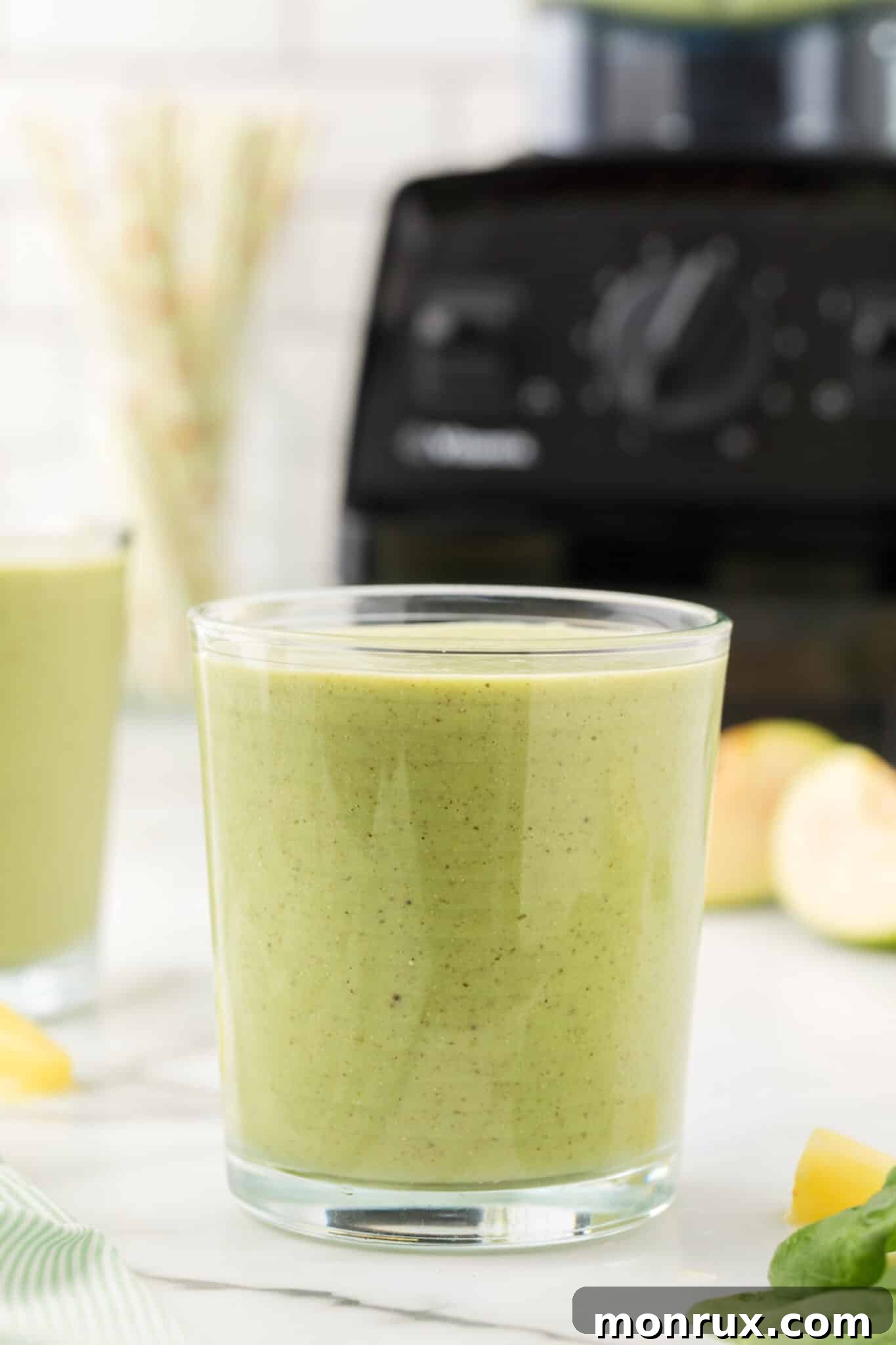 A short glass filled with a vibrant green banana spinach smoothie, perfect for a healthy boost.