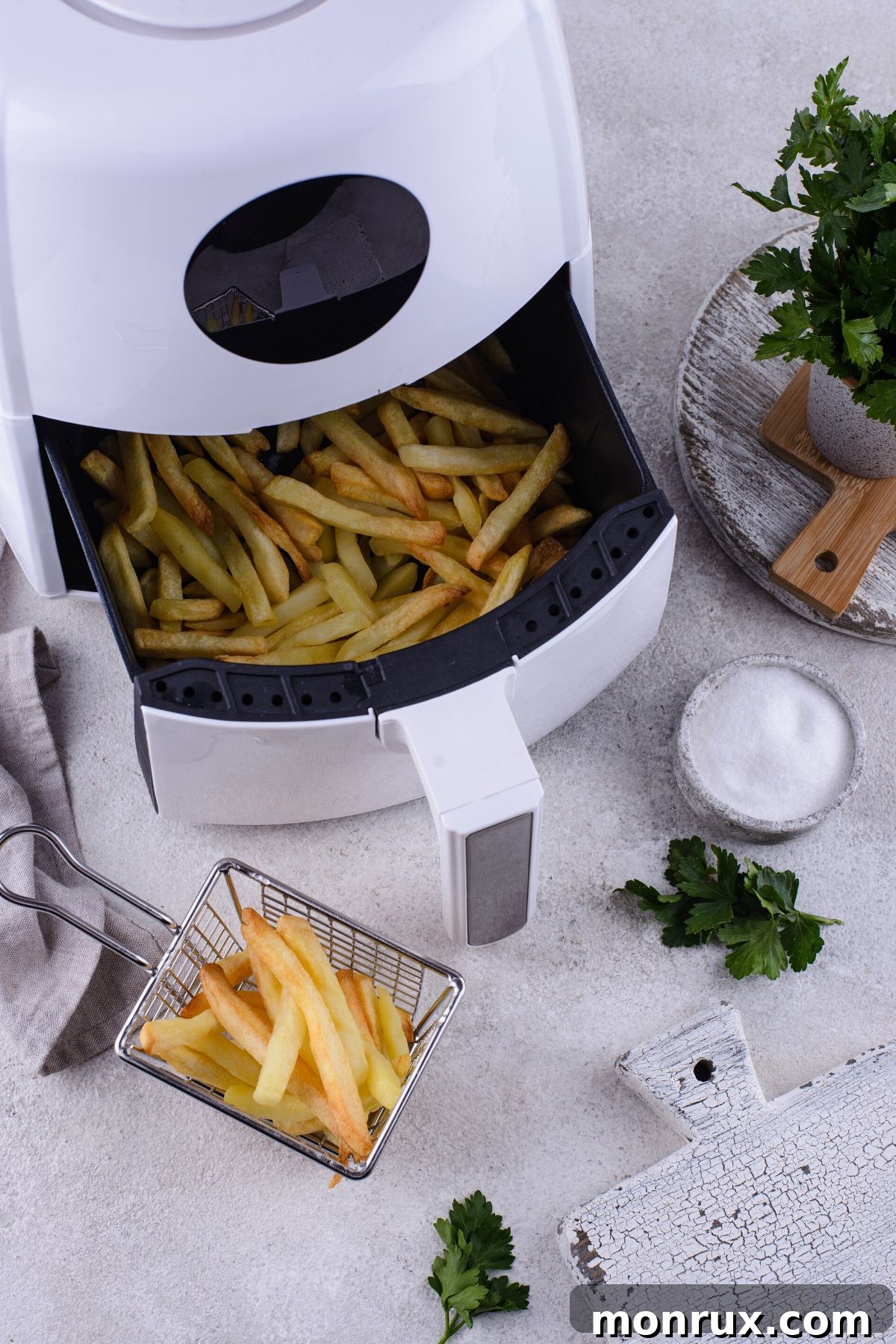 White air fryer open with a basket full of golden-brown, perfectly cooked fries ready to be served.