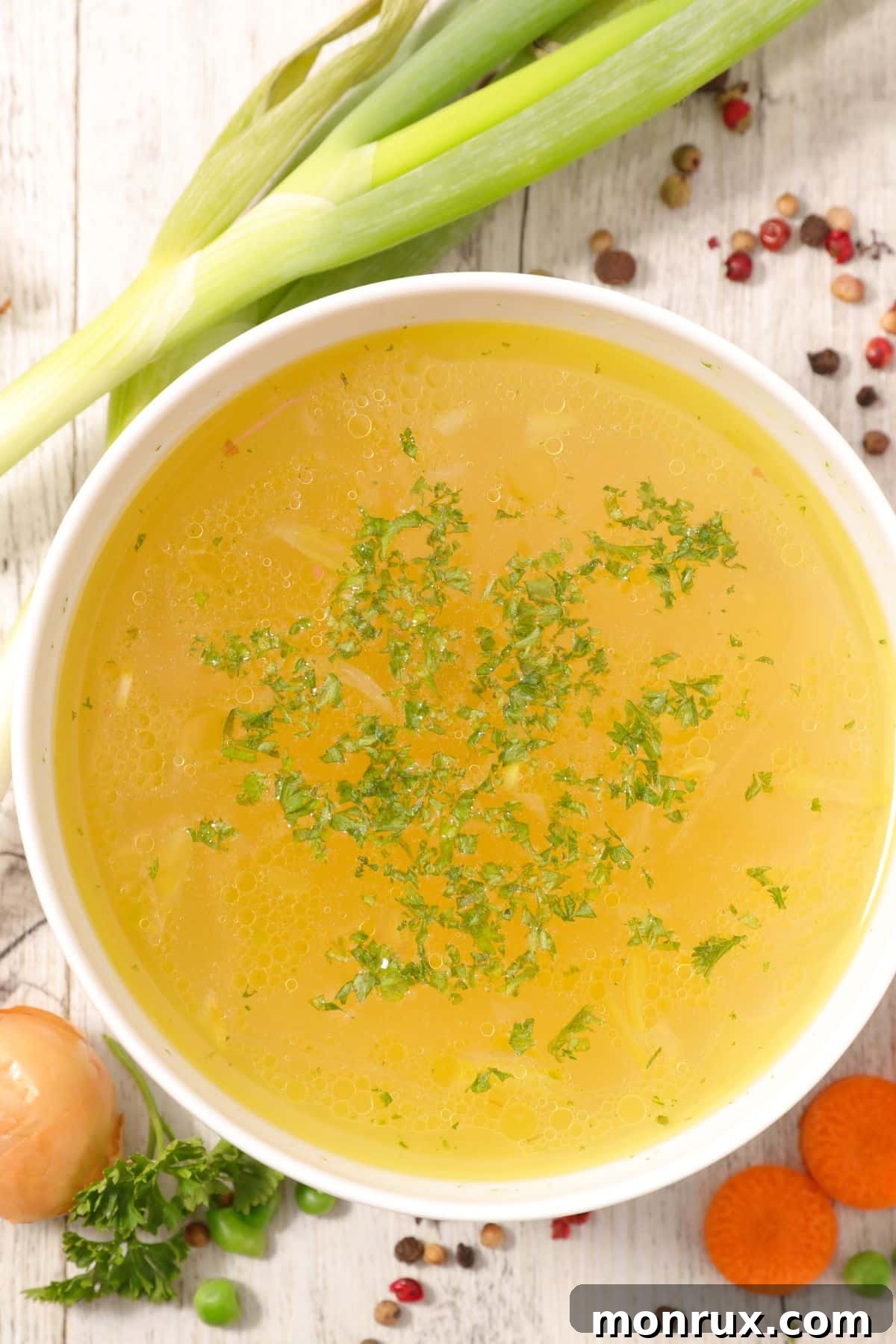 Bowl of vegetable bouillon on wooden surface.