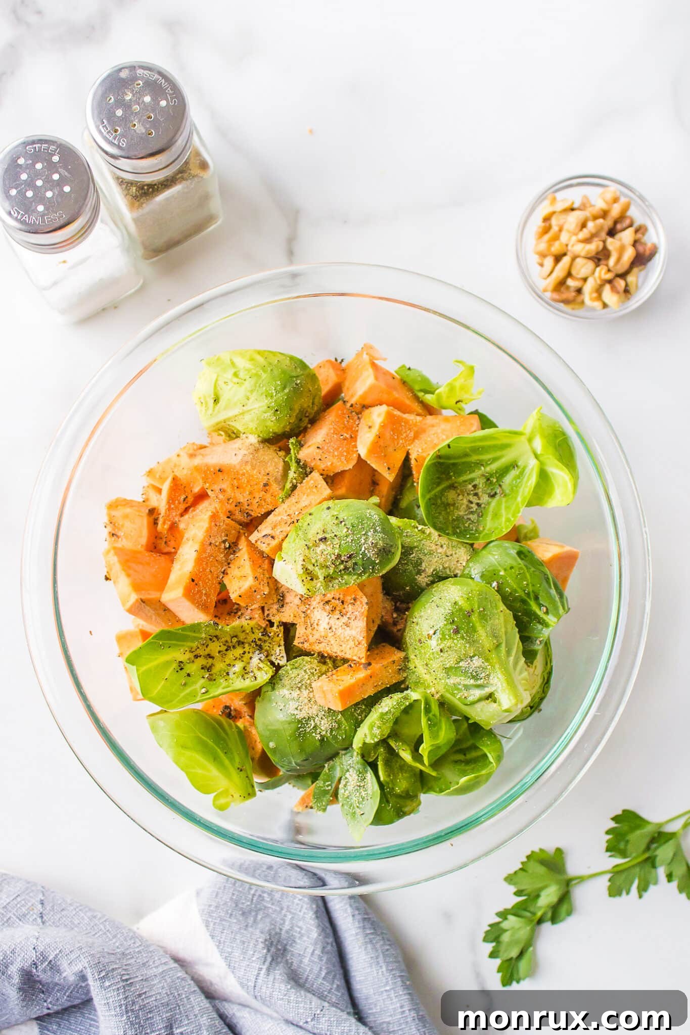 Freshly prepped Brussels sprouts and sweet potatoes in a mixing bowl.