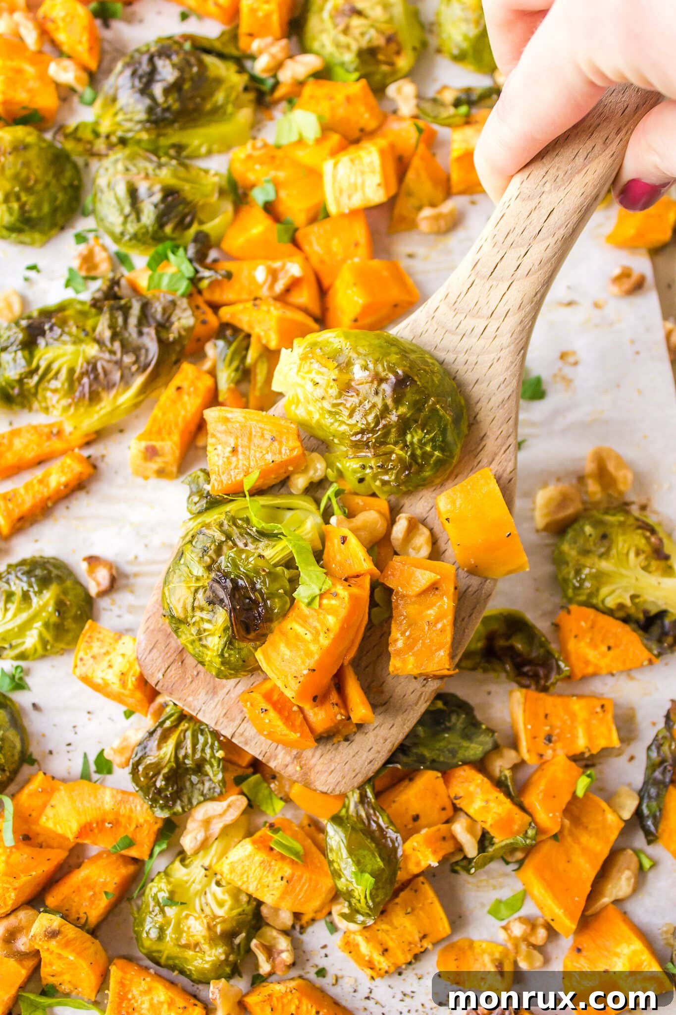 Roasted Brussels sprouts and sweet potatoes garnished with walnuts and parsley, ready to be served.