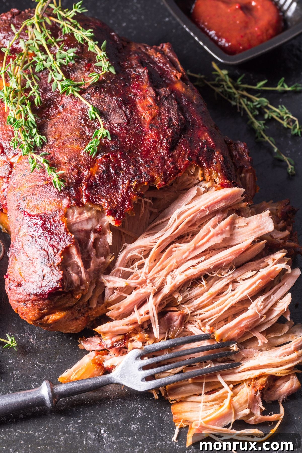 A fork shredding a roasted pork loin, emphasizing the tender, pull-apart texture of perfectly cooked pork.