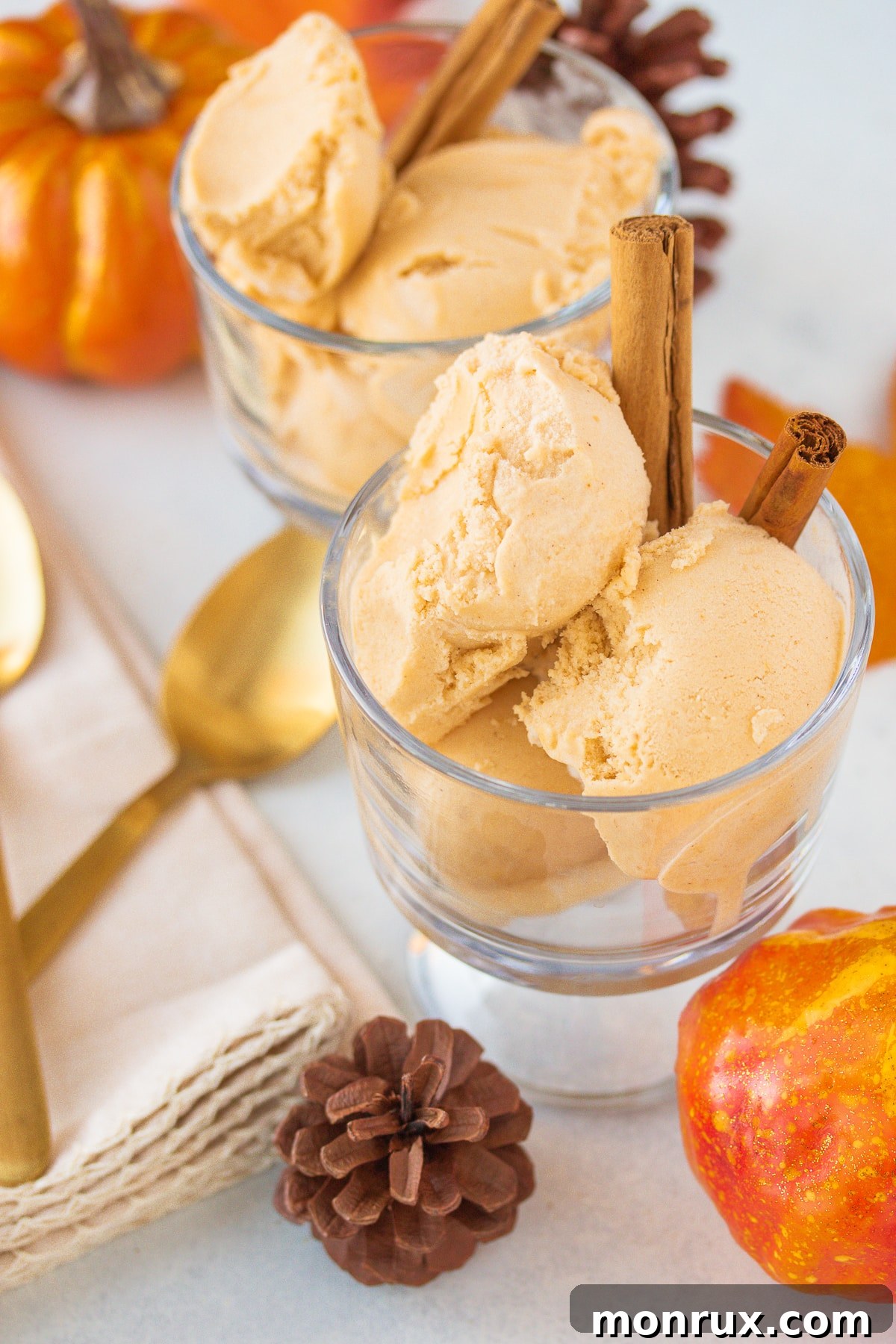 Two bowls of creamy pumpkin ice cream with cinnamon sticks, a delightful soft dessert.