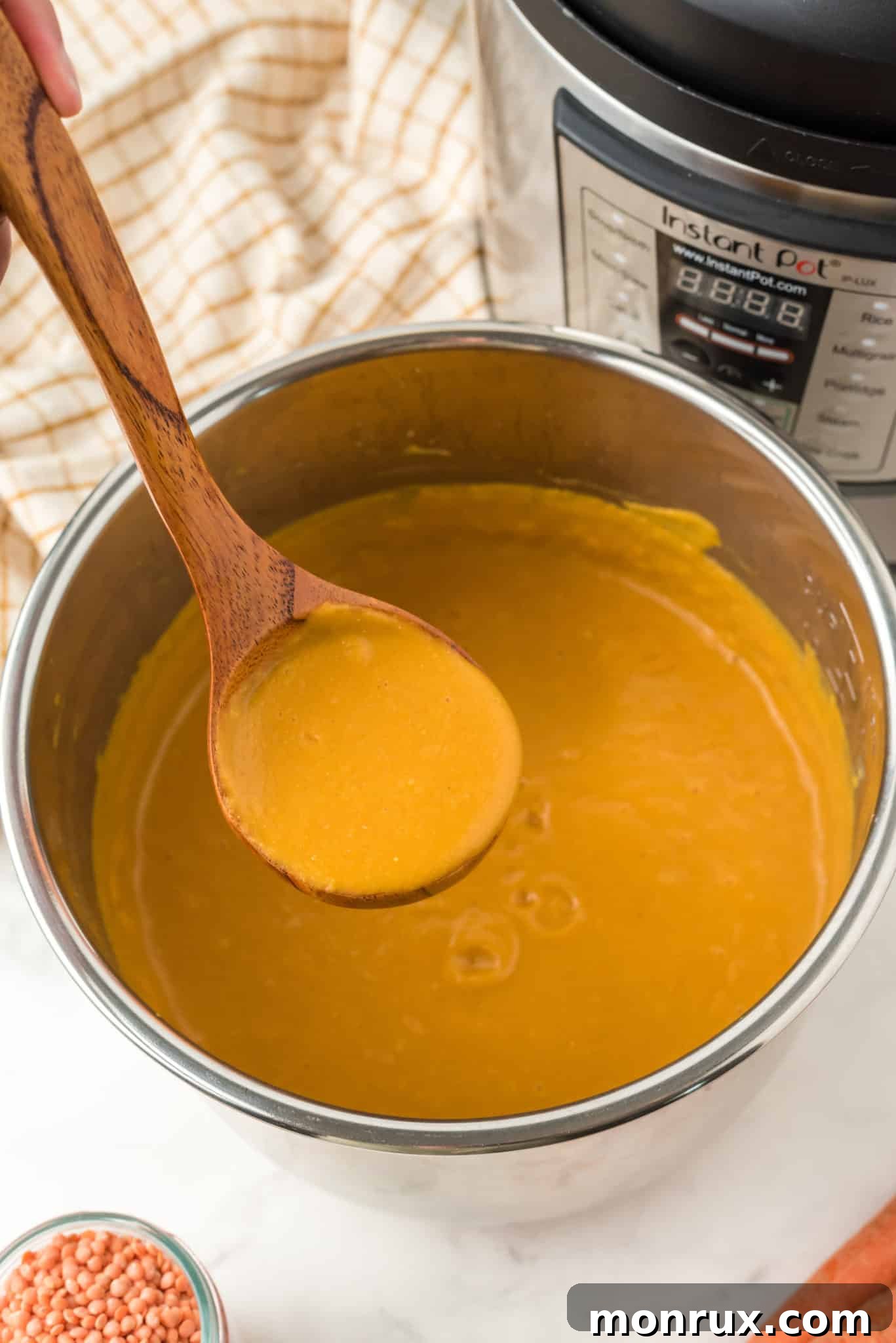 A ladle serving creamy Instant Pot Carrot Ginger Soup, ideal for a soft diet.