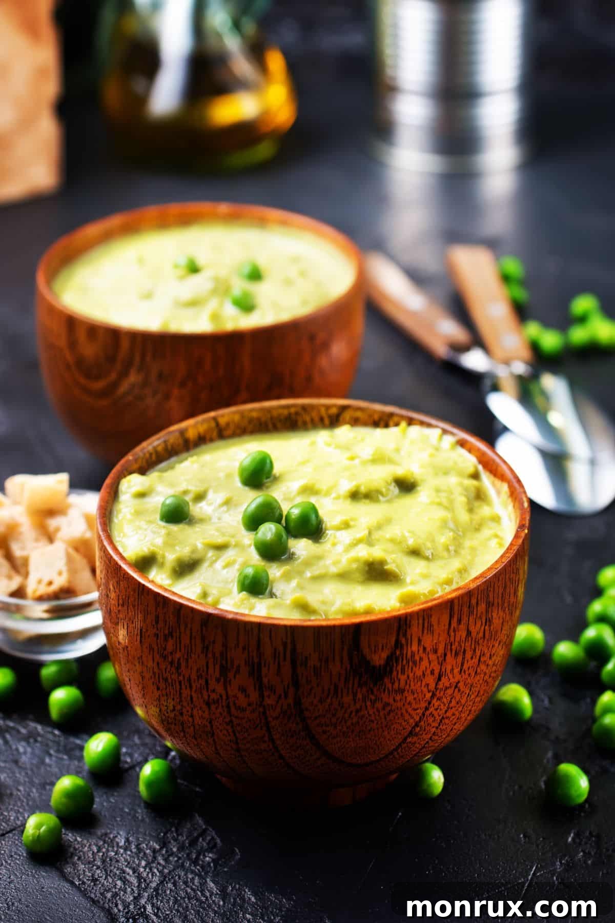 A wooden bowl filled with mashed green peas, a soft and nutritious vegetable option.