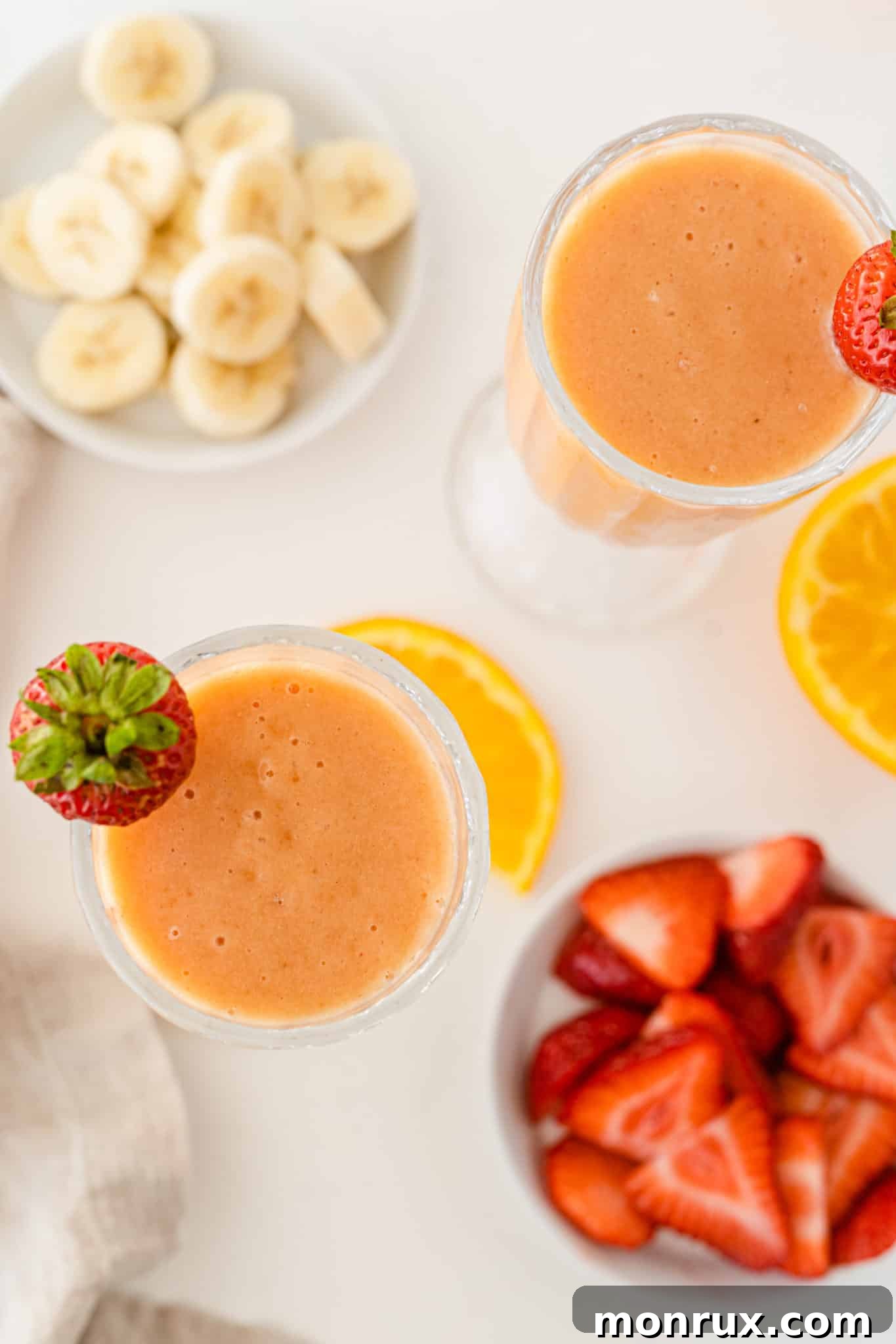 Two refreshing glasses of mango strawberry banana smoothie, a nutrient-packed soft drink.