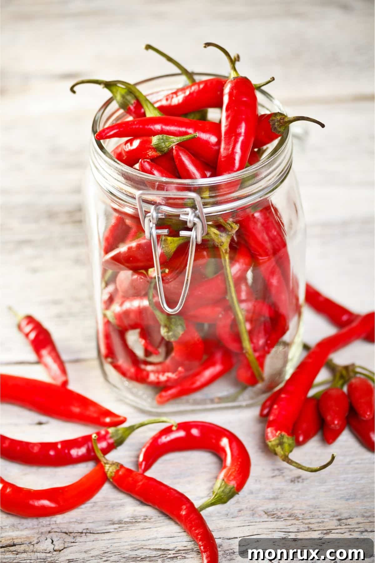 Jar of chili peppers on wooden surface.