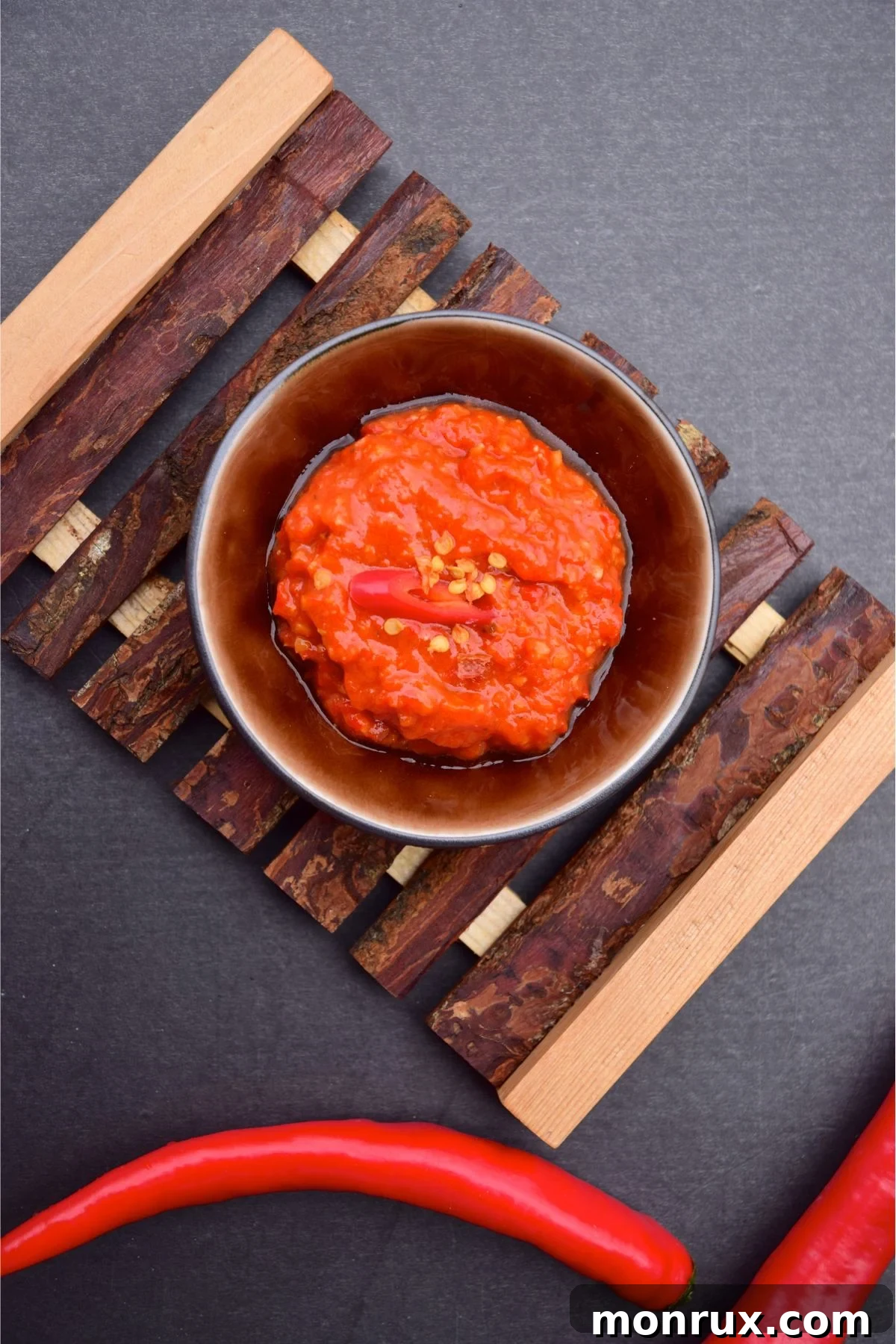 Bowl of red chili paste on wooden mat.