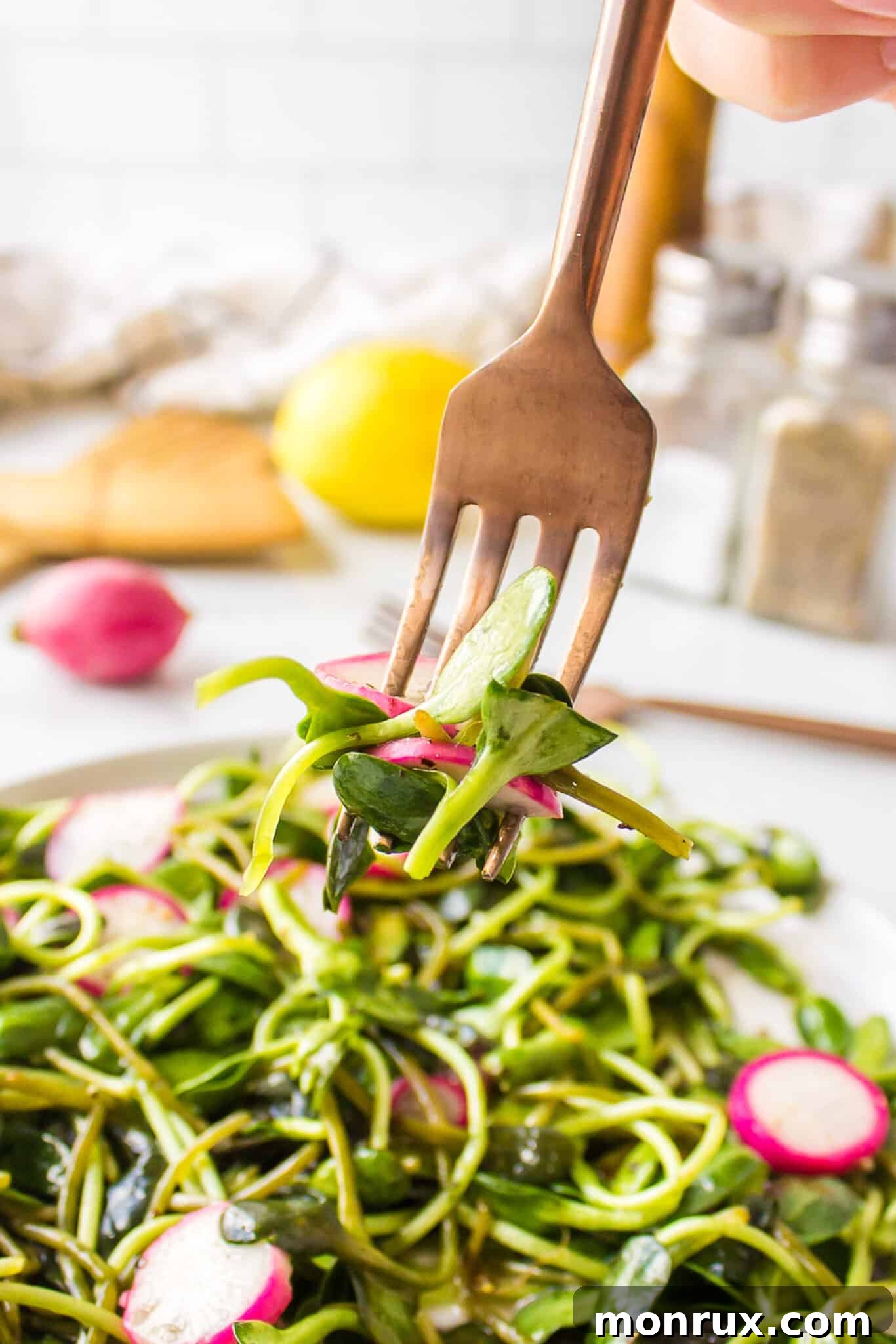A fork lifts a vibrant bite of Microgreens Salad from a white plate, showcasing the freshness and texture of the ingredients.