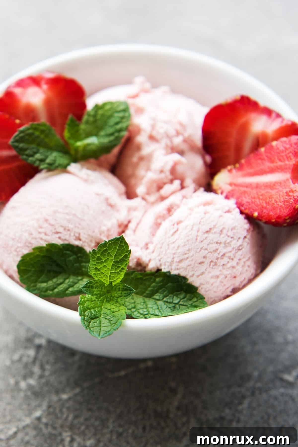 Bowl of dairy-free strawberry ice cream, garnished with fresh berries.