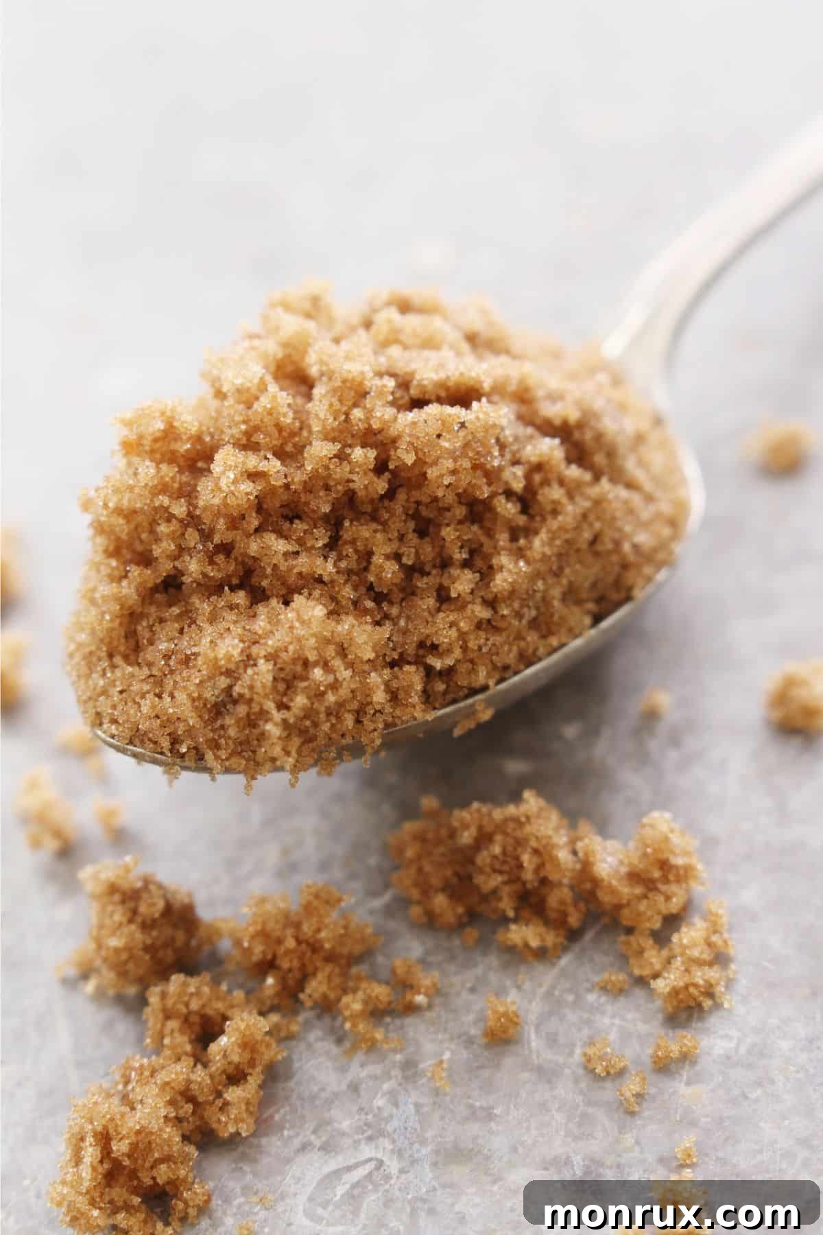 Spoonful of brown sugar on metal surface.