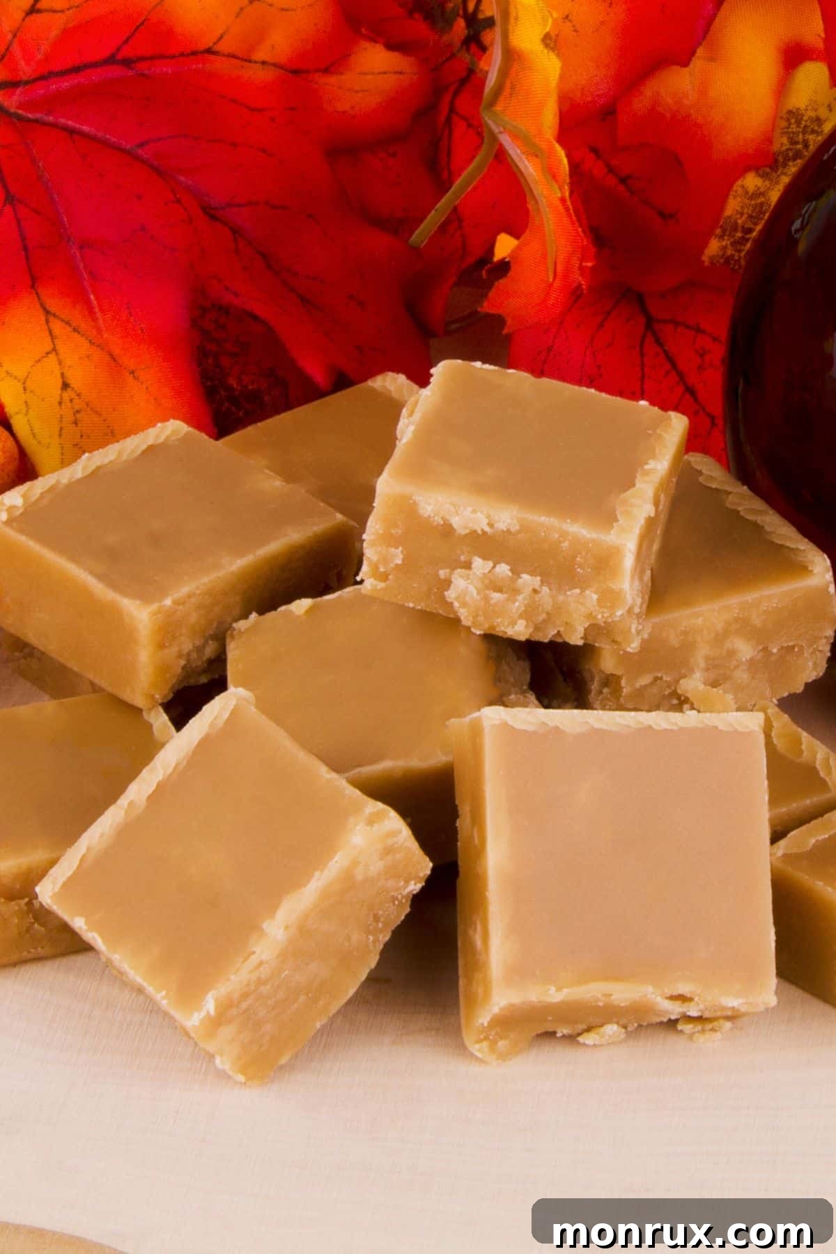Blocks of maple sugar on wooden surface with fall leaves.