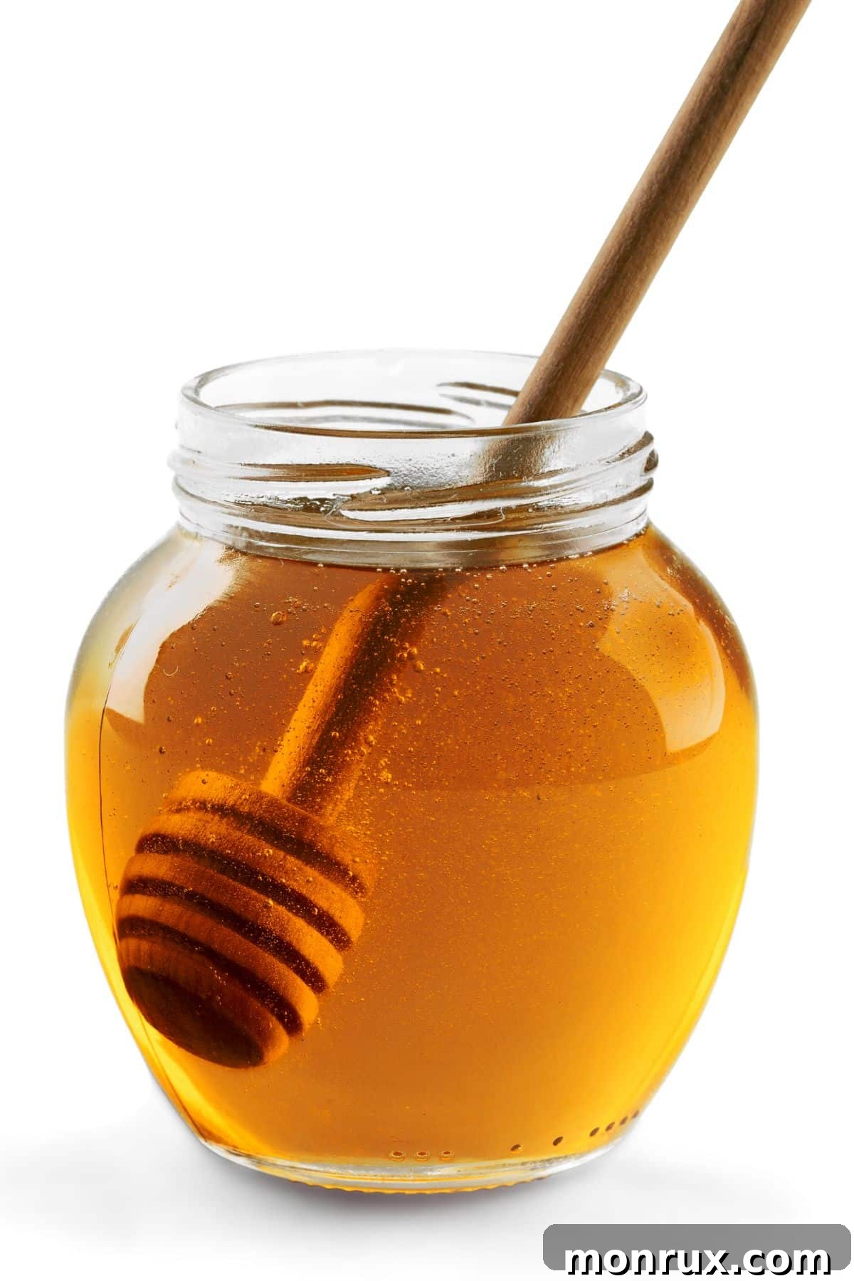 Bottle of honey with wooden honey stirrer and white background.