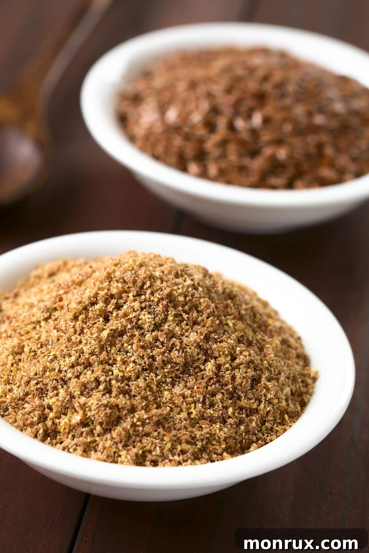 Bowl of ground flax on wooden surface.