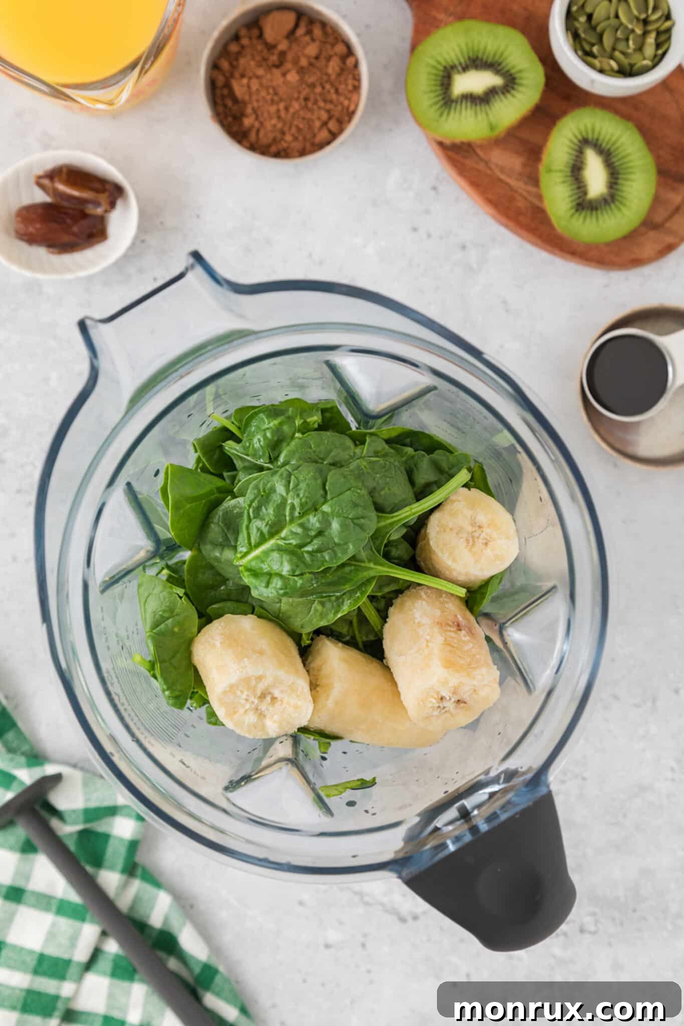 A blender jar with fresh spinach and chunks of frozen banana, captured from a top-down view, ready for blending into an iron-rich smoothie.