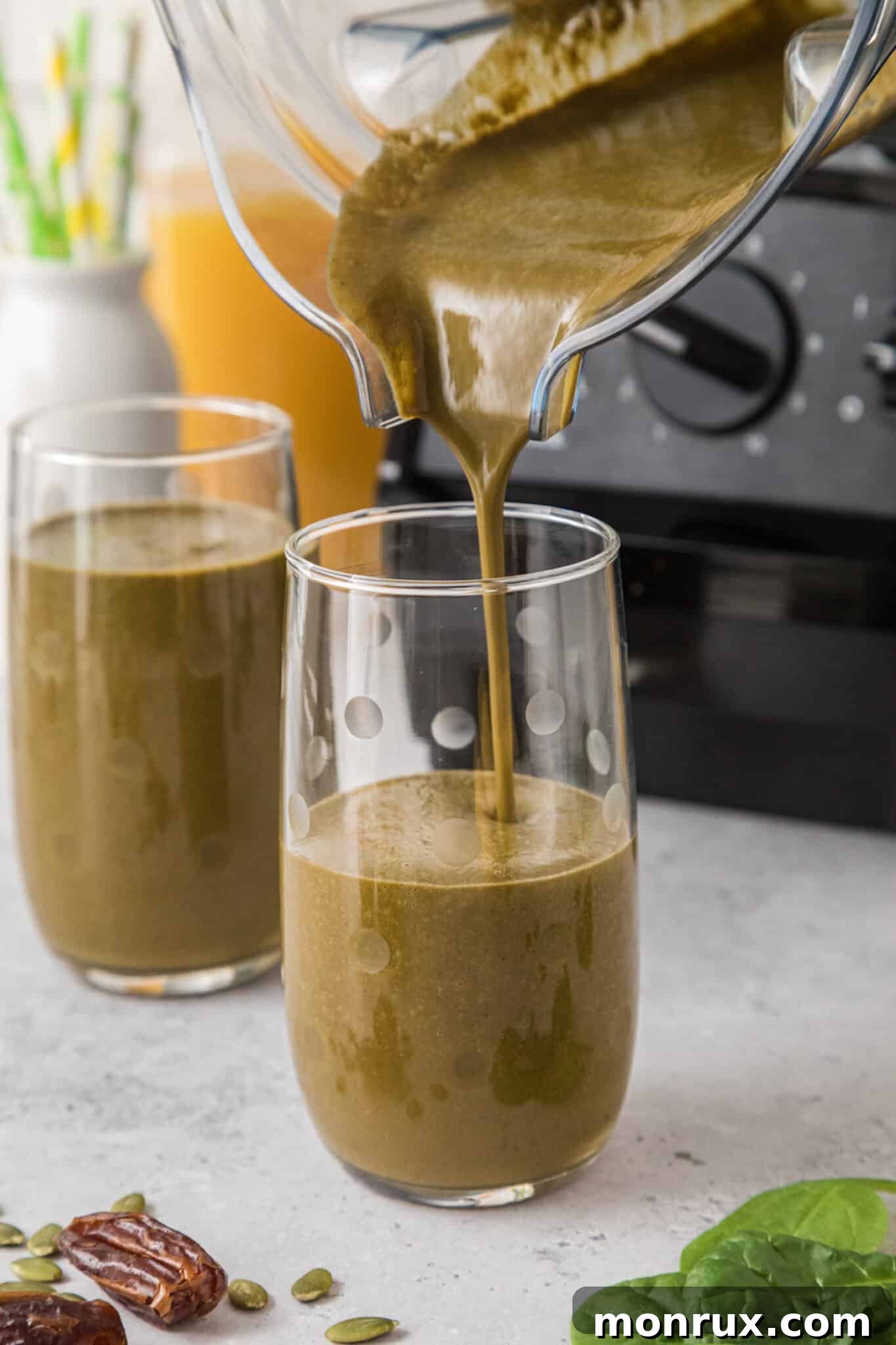 A blender jar smoothly pouring a rich, green iron-rich smoothie into a tall glass, highlighting the creamy texture.