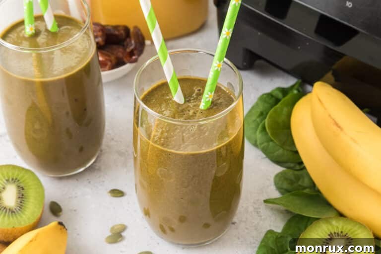A glass of iron rich green smoothie with two green striped straws.