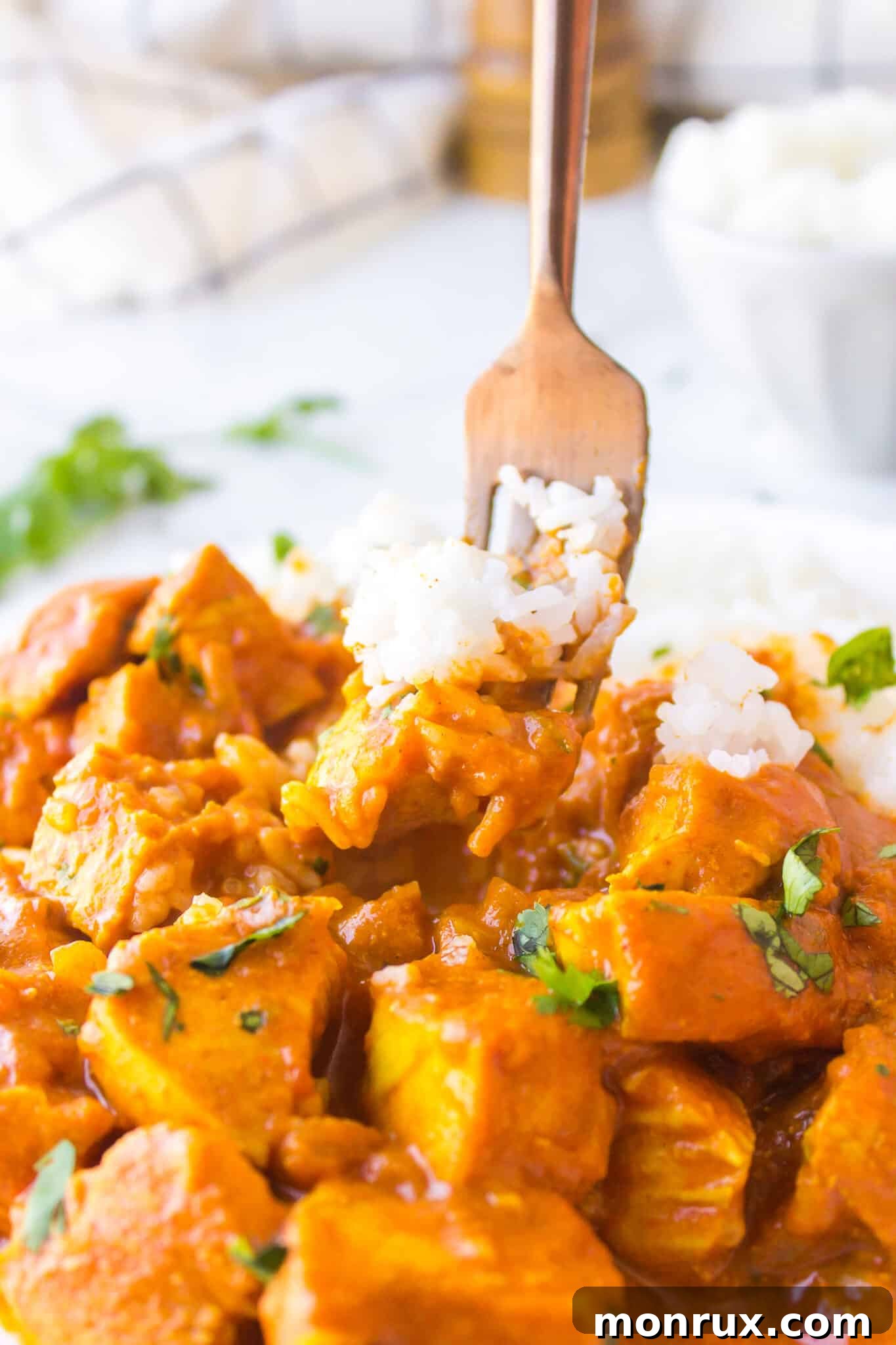 A fork lifting a perfect bite of creamy chicken curry with white rice, showcasing the tender chicken and rich sauce.