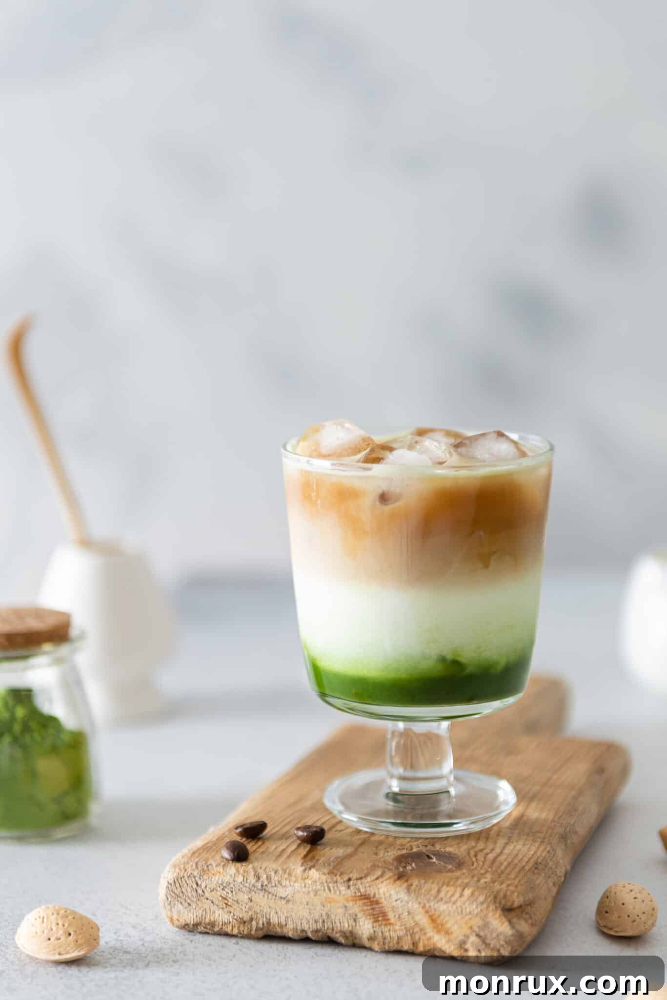 A beautifully layered iced matcha green tea espresso on a rustic wooden board, showcasing vibrant green and rich brown hues.