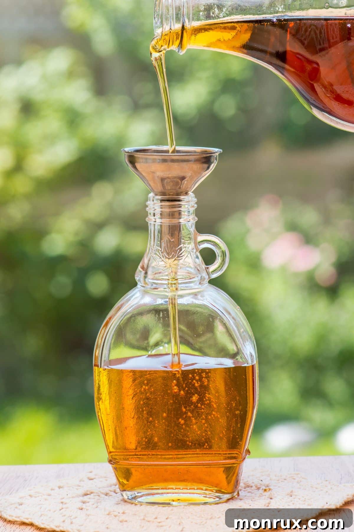 Maple syrup pouring into funnel filling a jar.