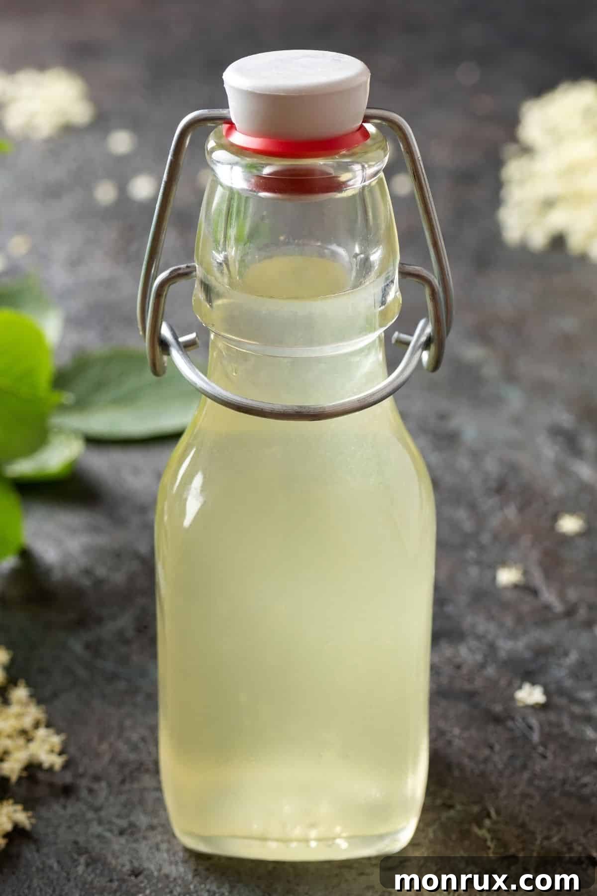 Jar of simple syrup on dark surface.
